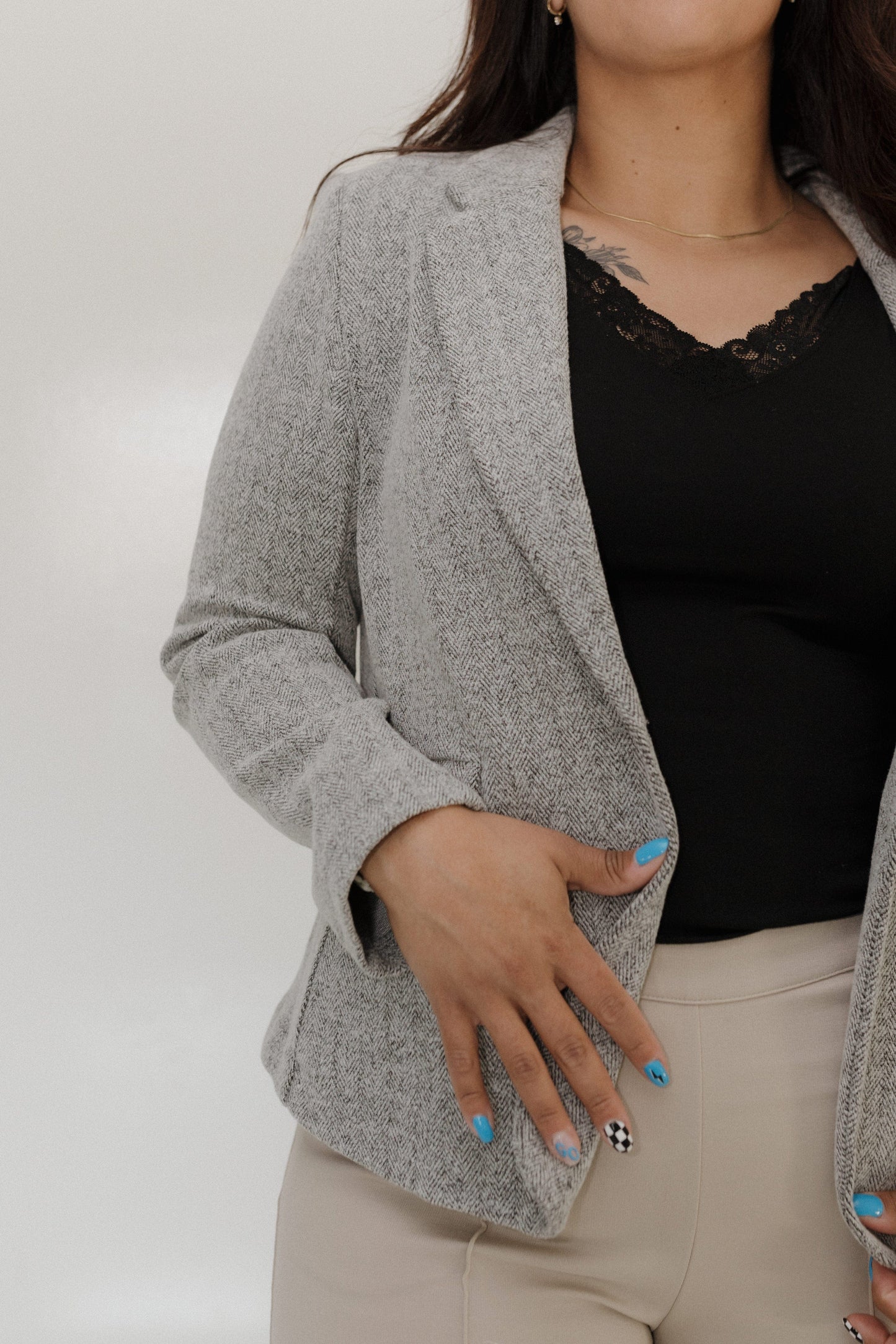 Person wearing a gray blazer over a black top with a neutral background