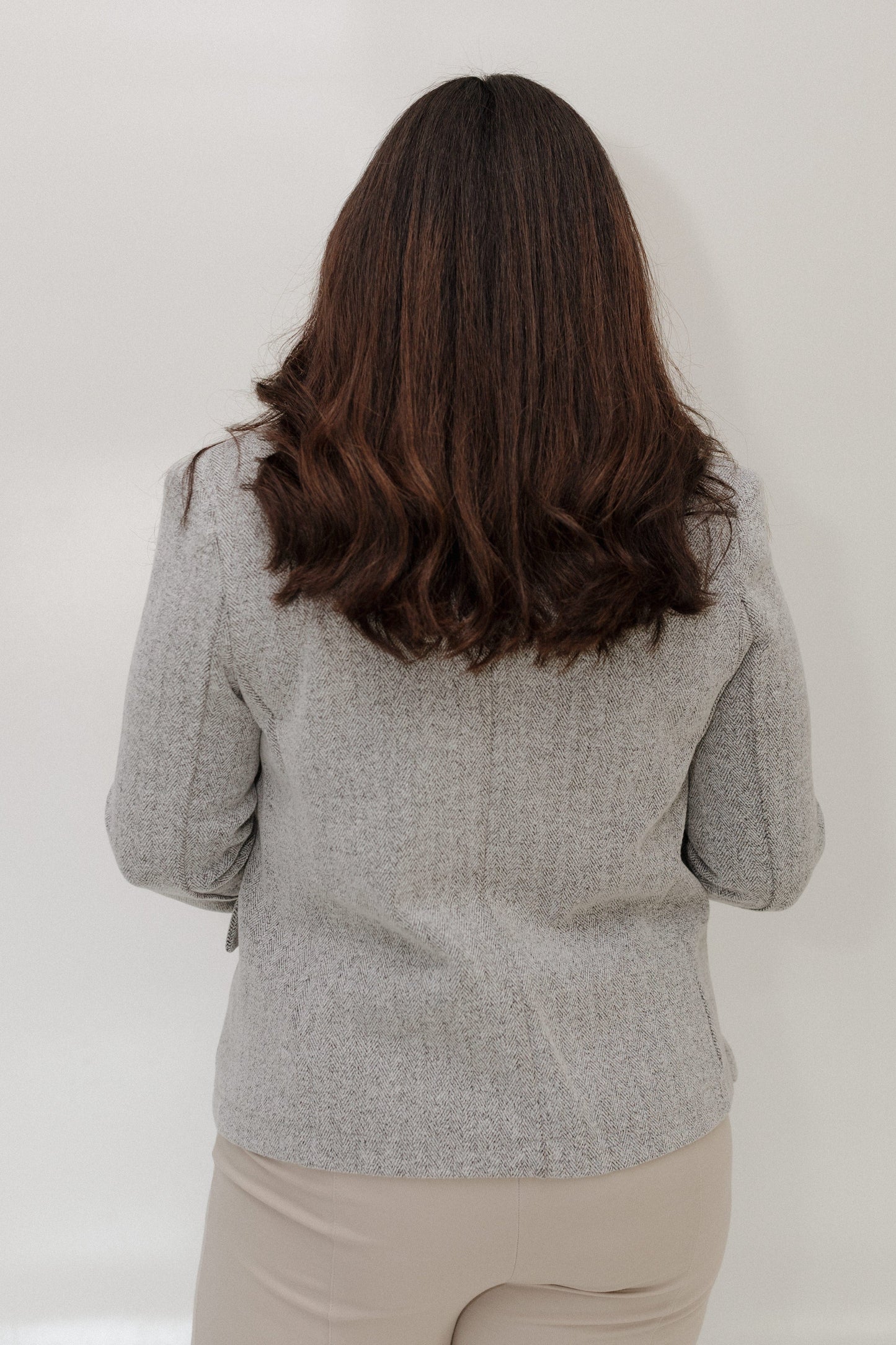 Person wearing a gray blazer against a white background