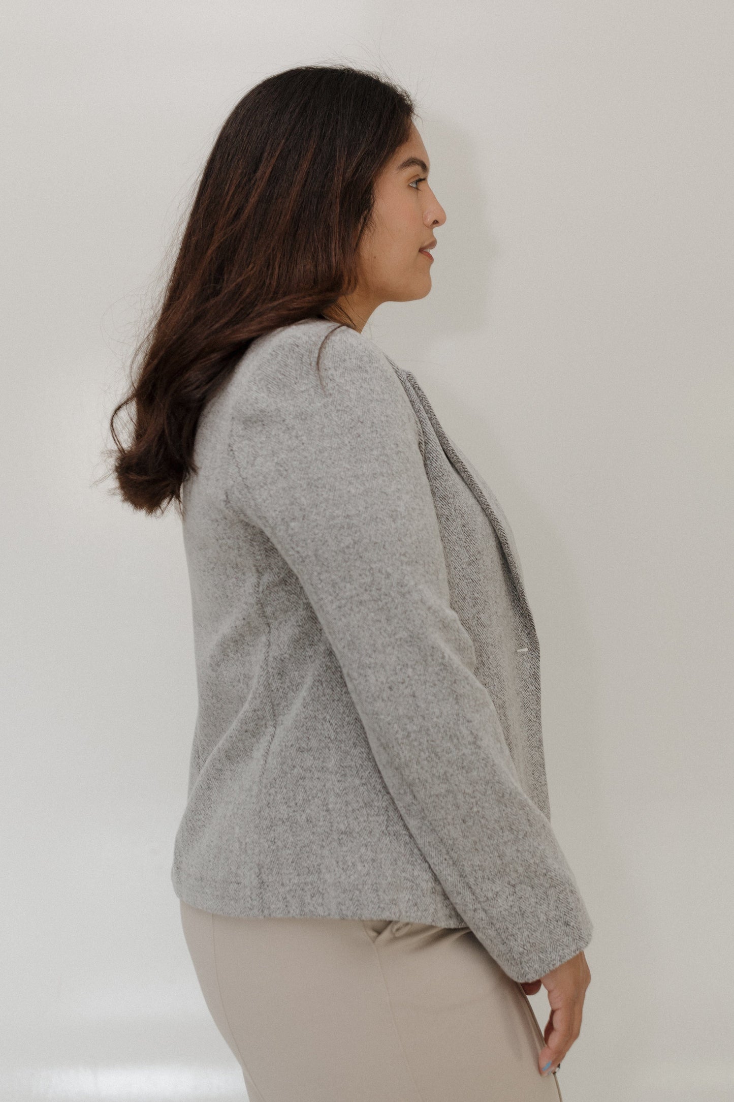 Woman wearing a gray sweater against a plain background