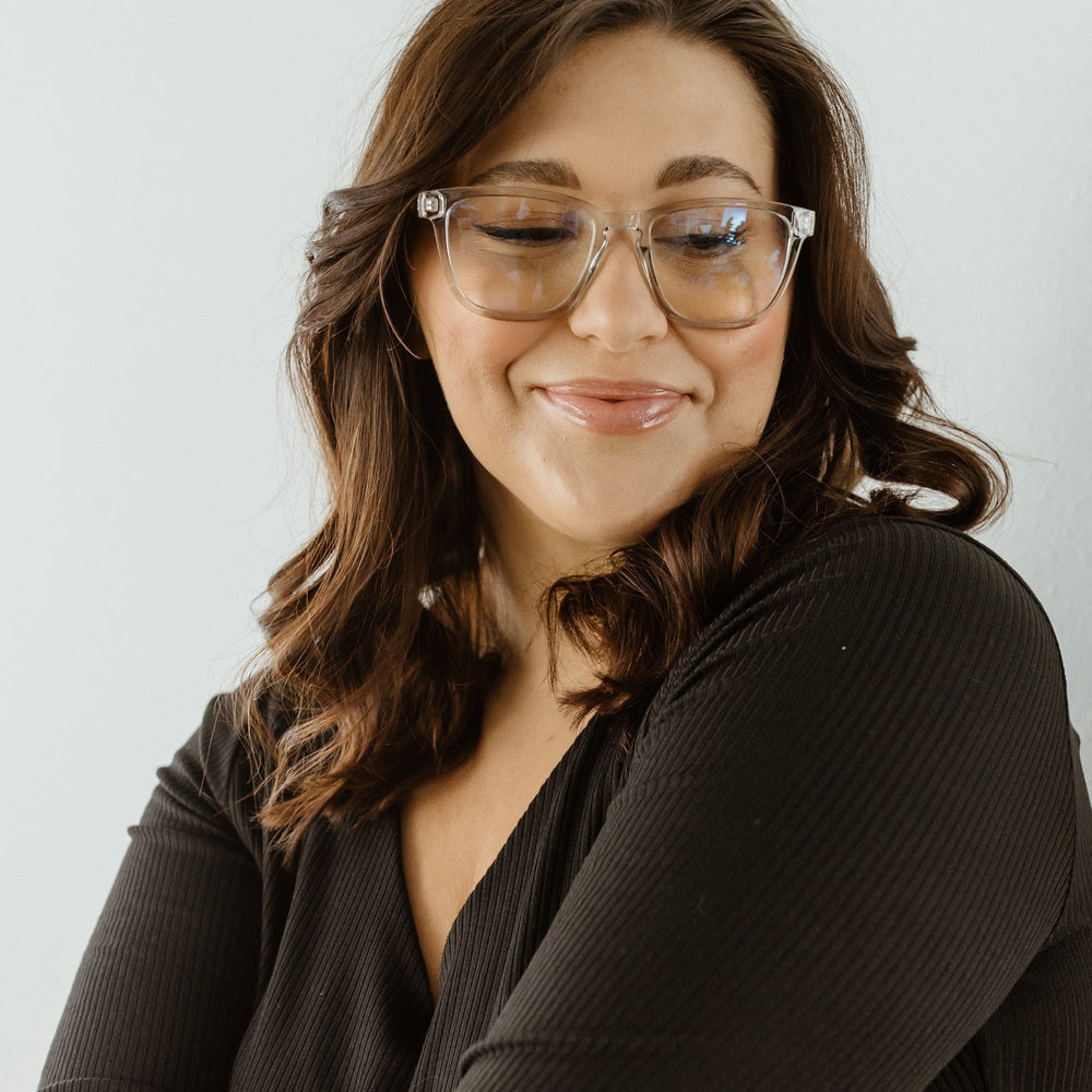 Woman wearing glasses and a black top against a light background