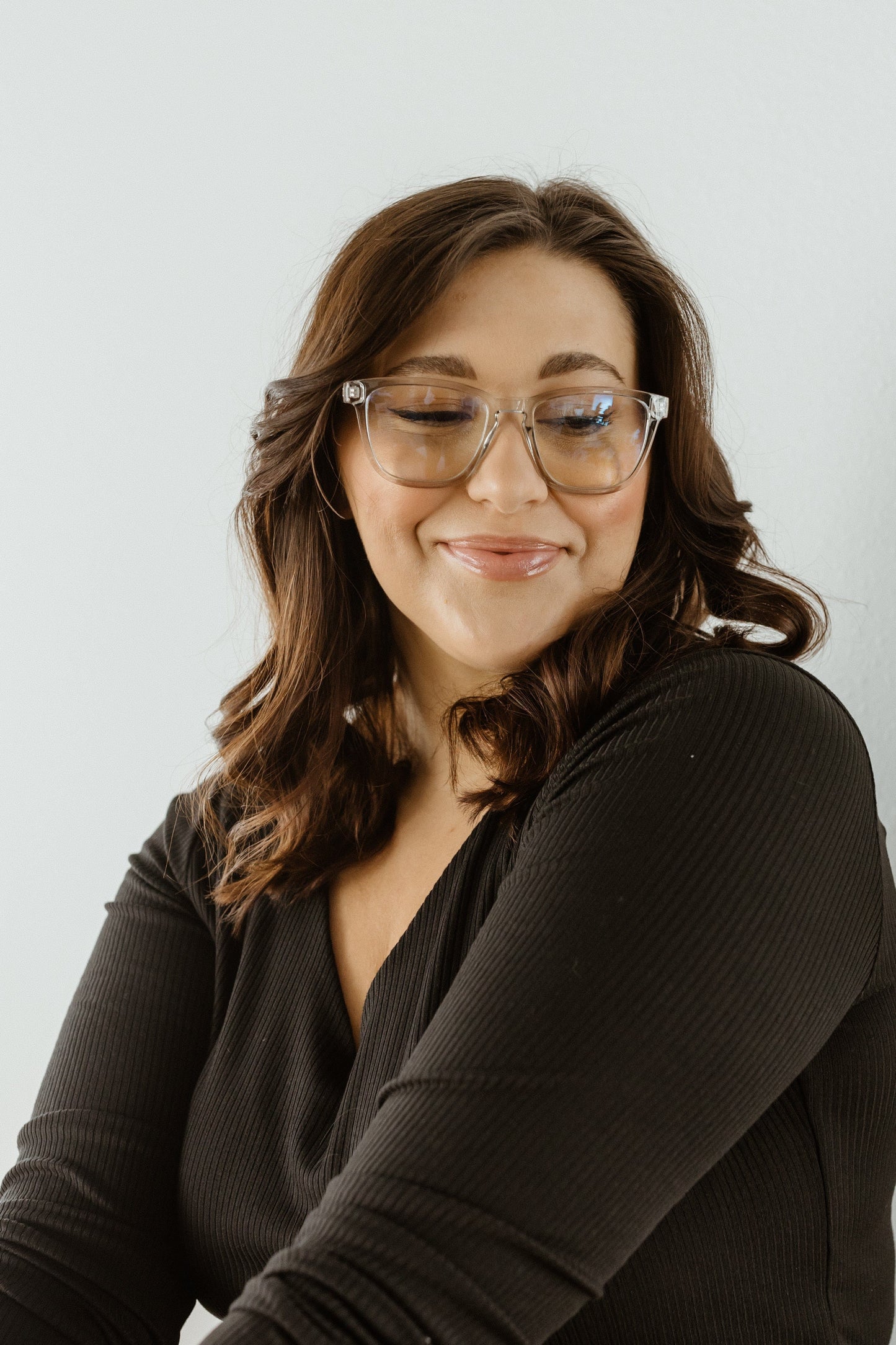 Woman wearing glasses and a black top against a light background