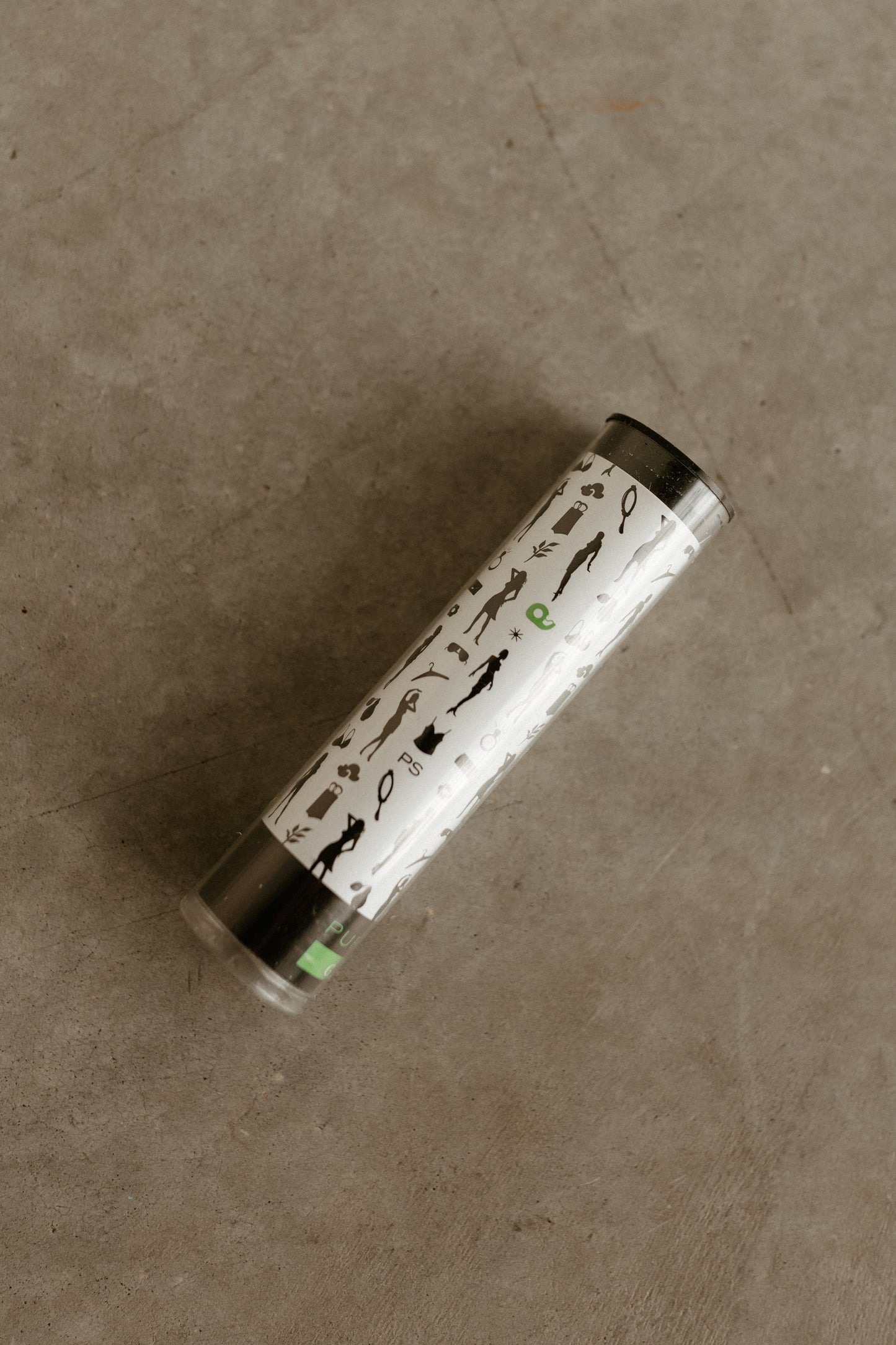 A cylindrical lipstick tube with a white cap features black and green animal silhouettes, designed to avoid wardrobe malfunctions.