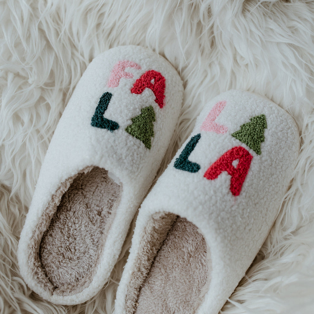 A pair of fuzzy slippers rests on a white fur surface, making them the perfect holiday gift.