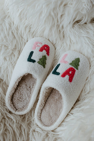 A pair of fuzzy slippers rests on a white fur surface, making them the perfect holiday gift.