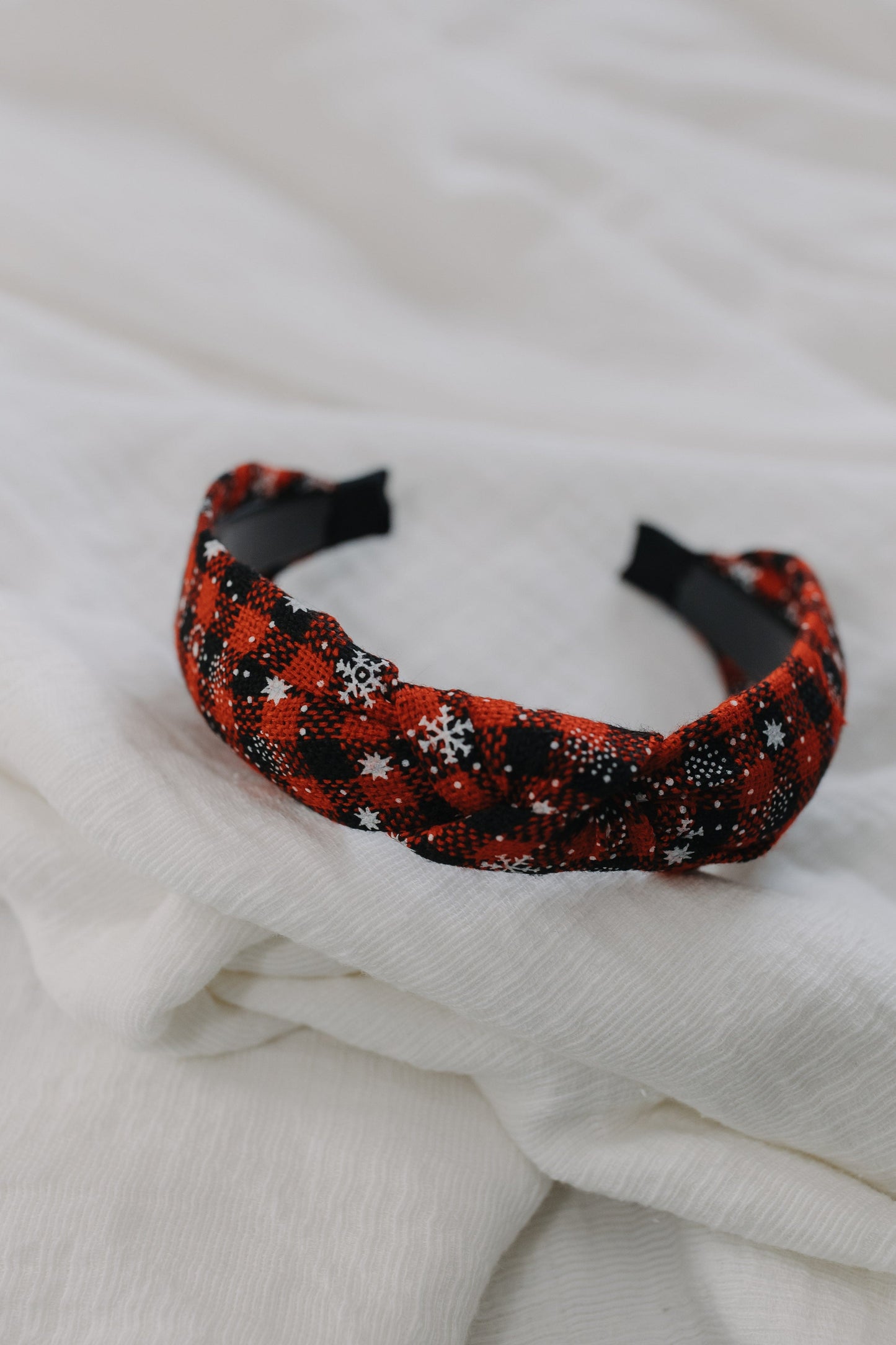 Red and black patterned headband on a white fabric background