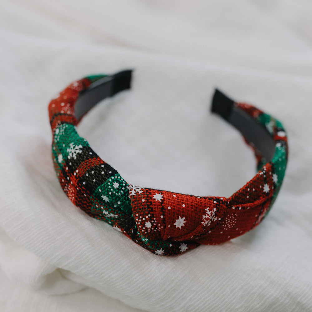 Decorative headband with red, green, and white pattern on a white fabric background