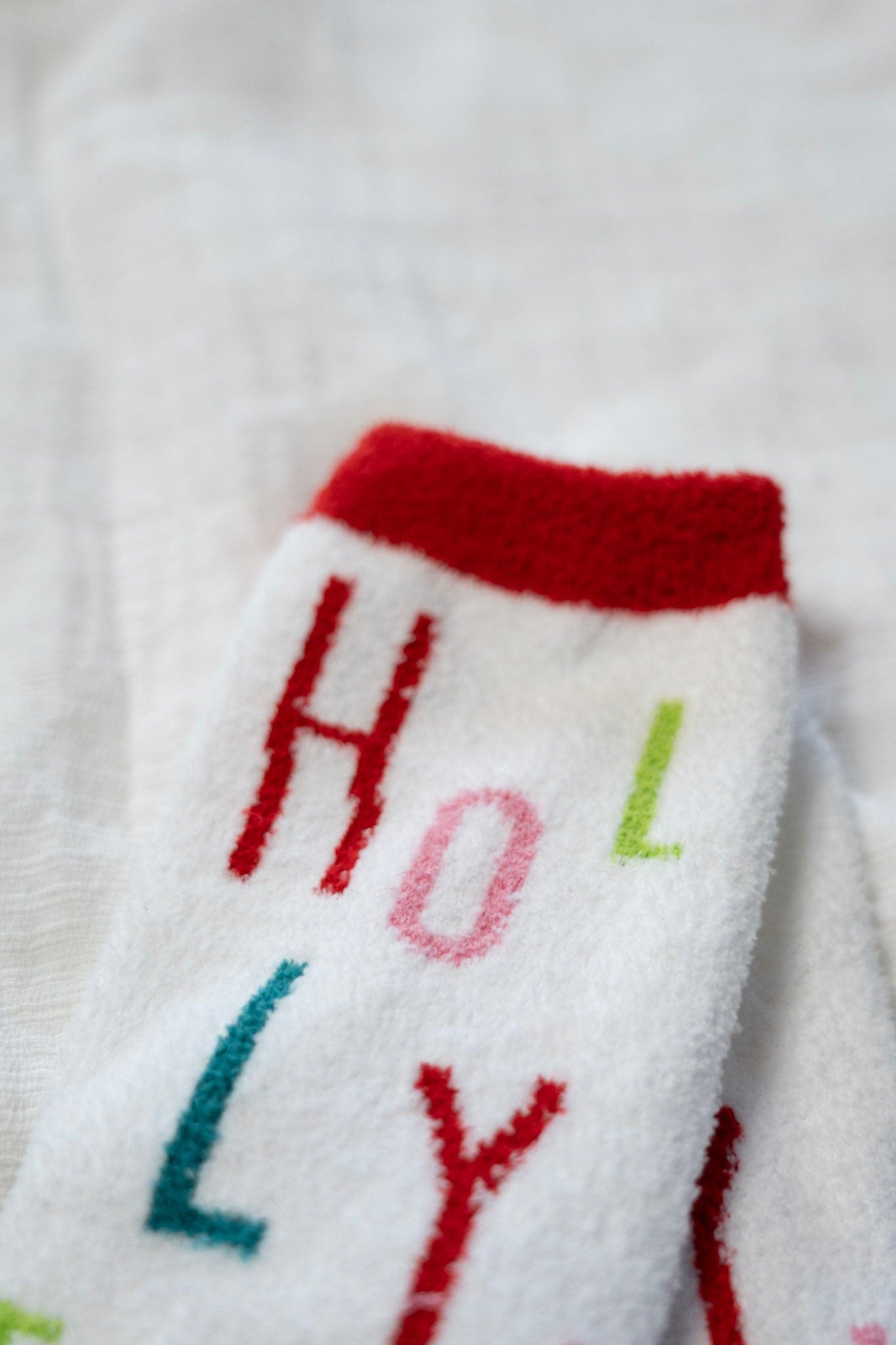 White socks with colorful letters spelling 'HOLLY' on a white background