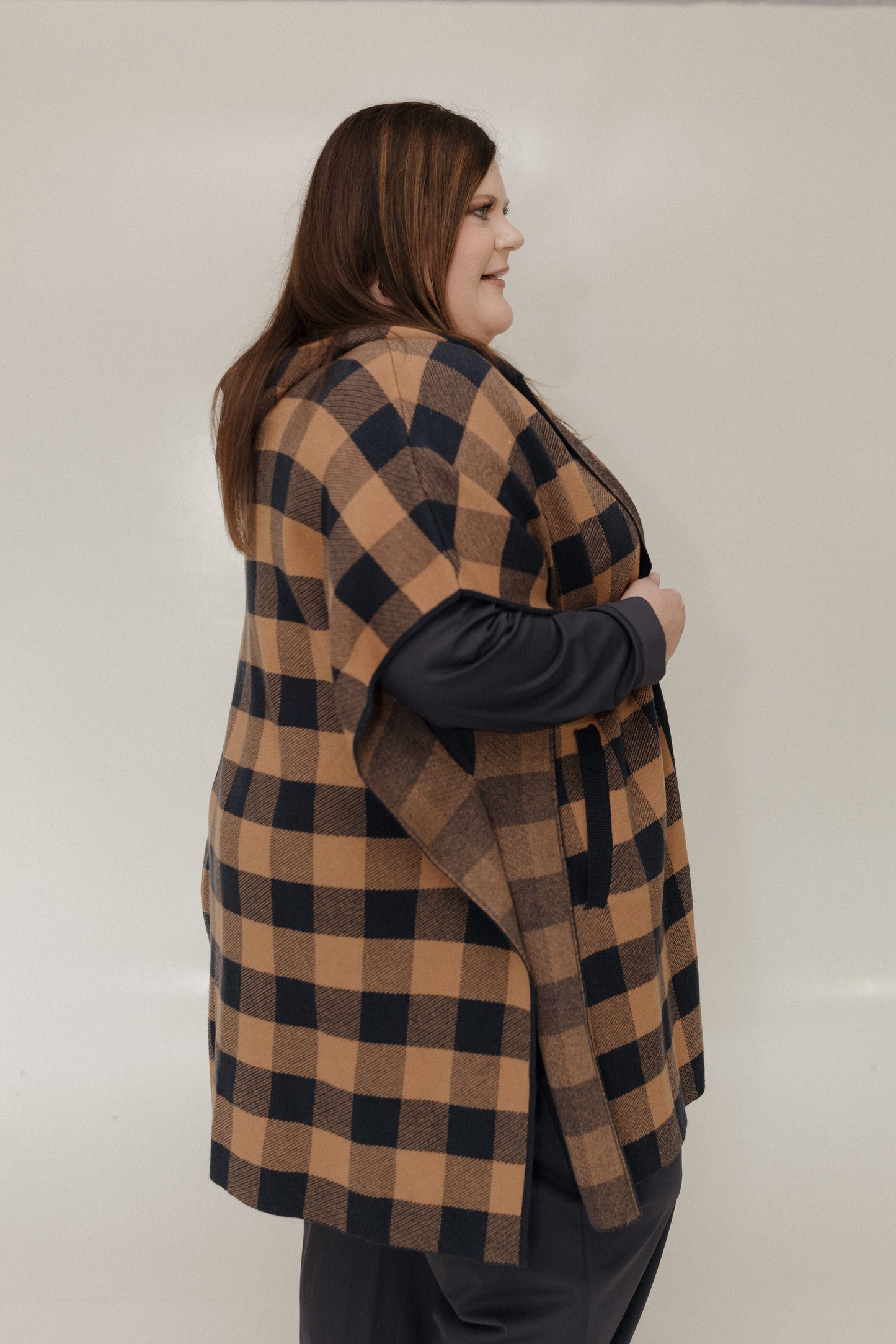 Person wearing a checkered vest over a dark long-sleeve shirt against a plain background