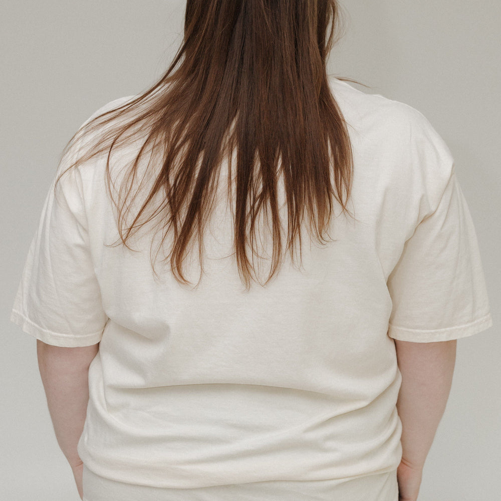 Person wearing a plain white t-shirt and light blue jeans against a neutral background