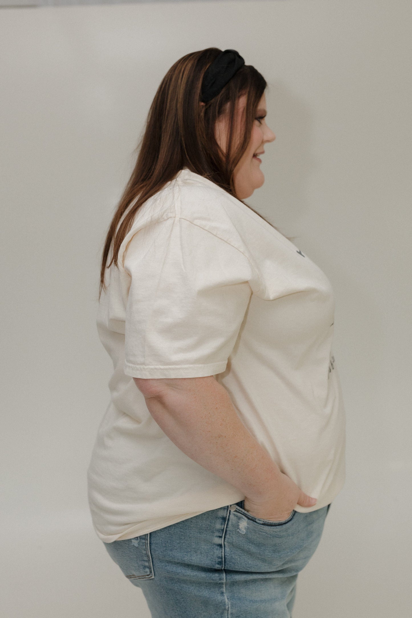 Woman wearing a white t-shirt and blue jeans against a plain background