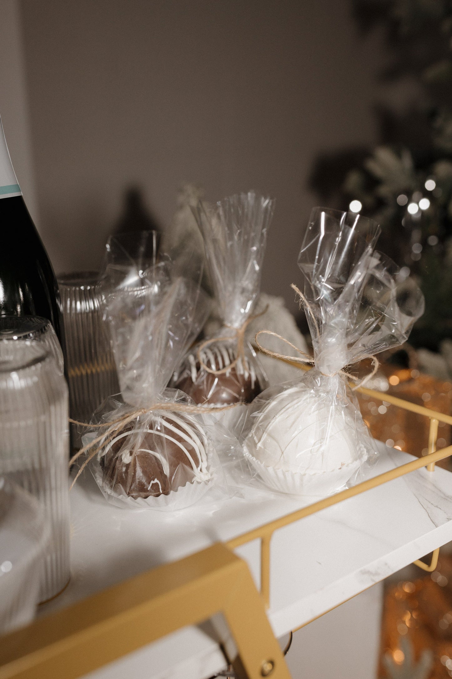 Decorative hot chocolate bombs wrapped in cellophane on a table with a blurred background