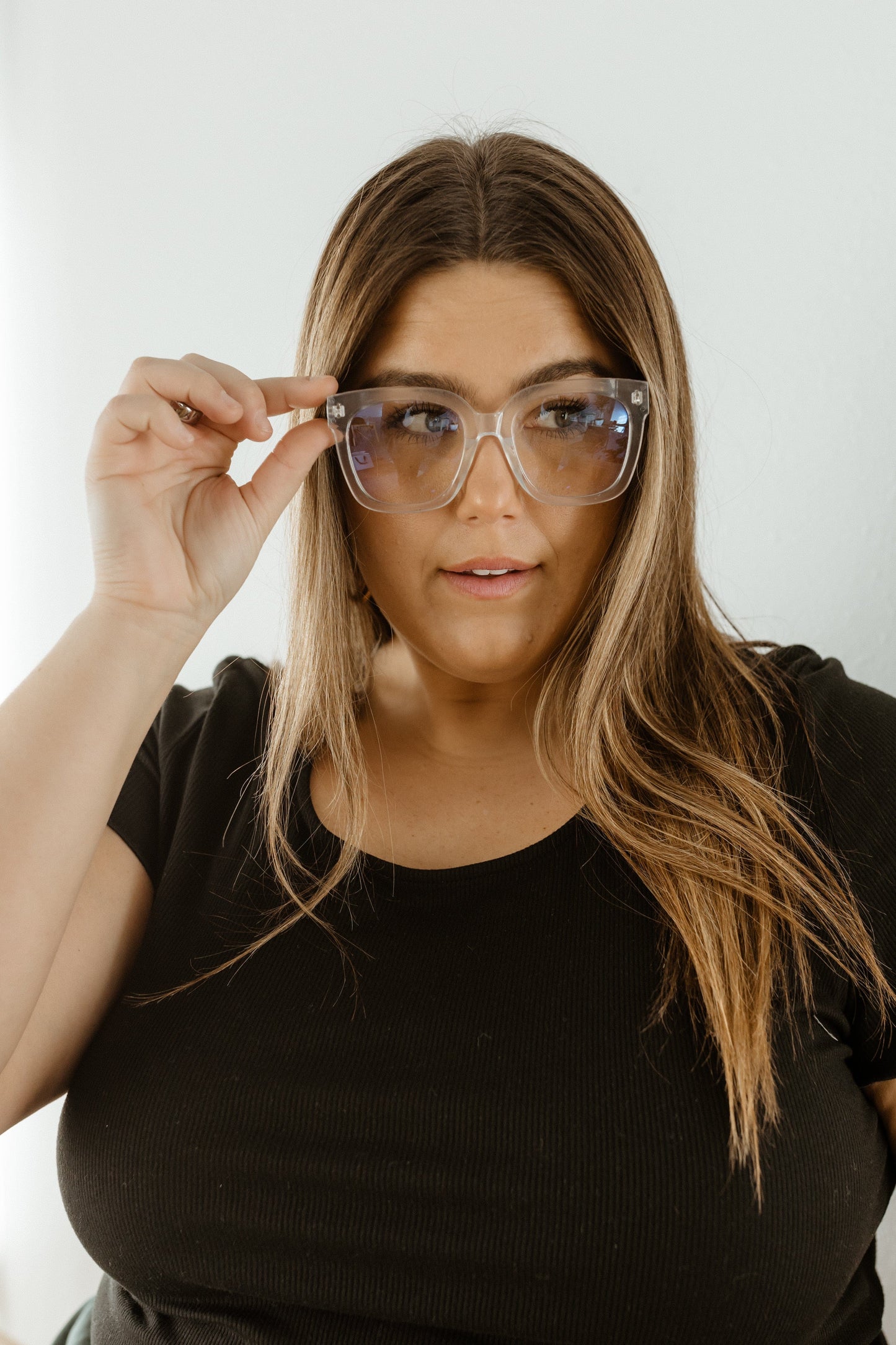 Woman wearing large clear glasses against a plain background