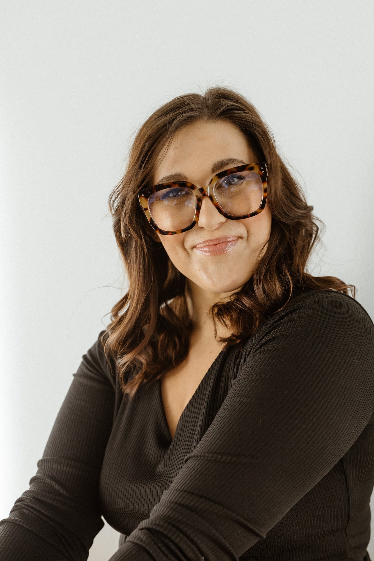 Woman wearing glasses and a dark top against a light background