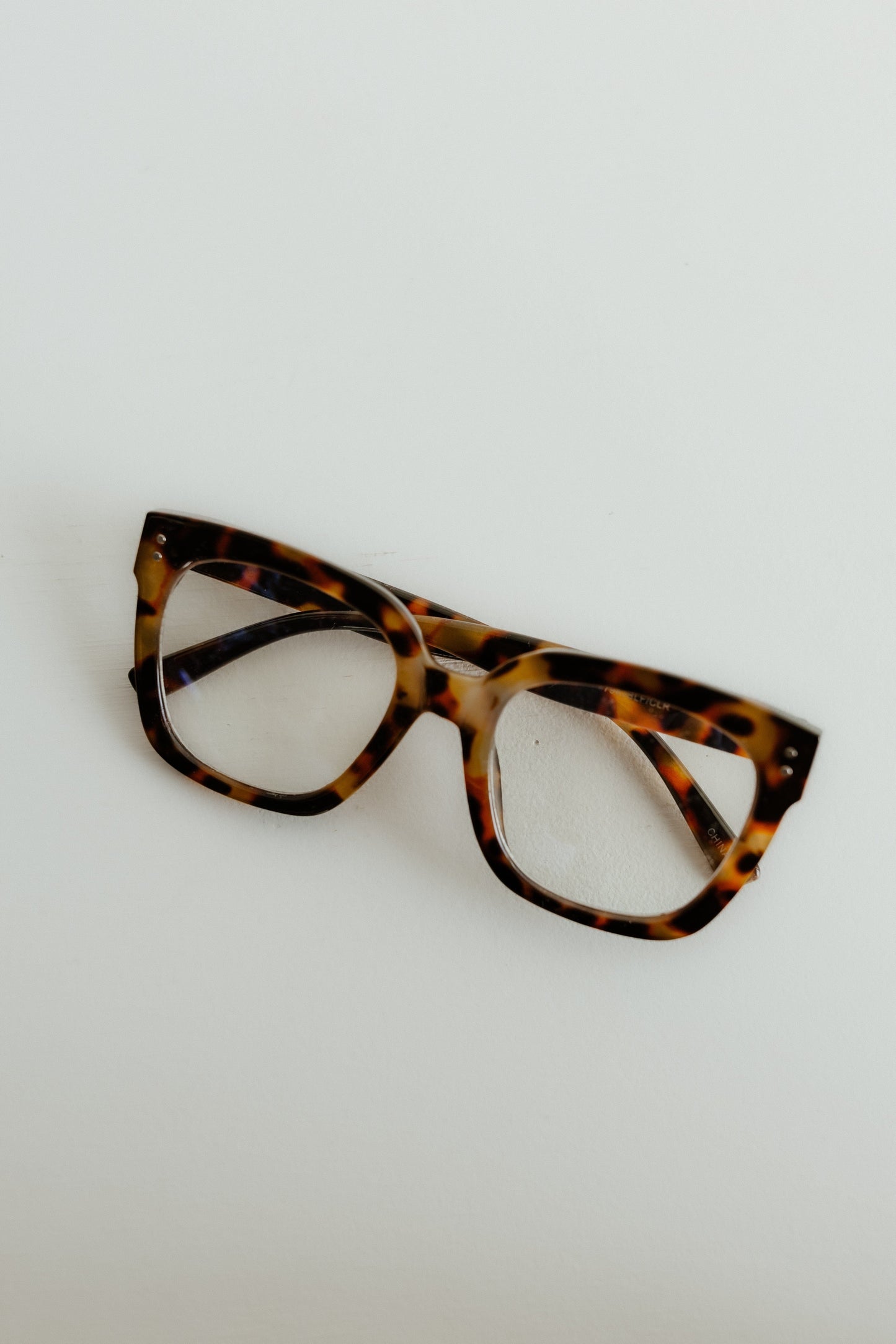 Tortoiseshell cat-eye glasses on a light gray background
