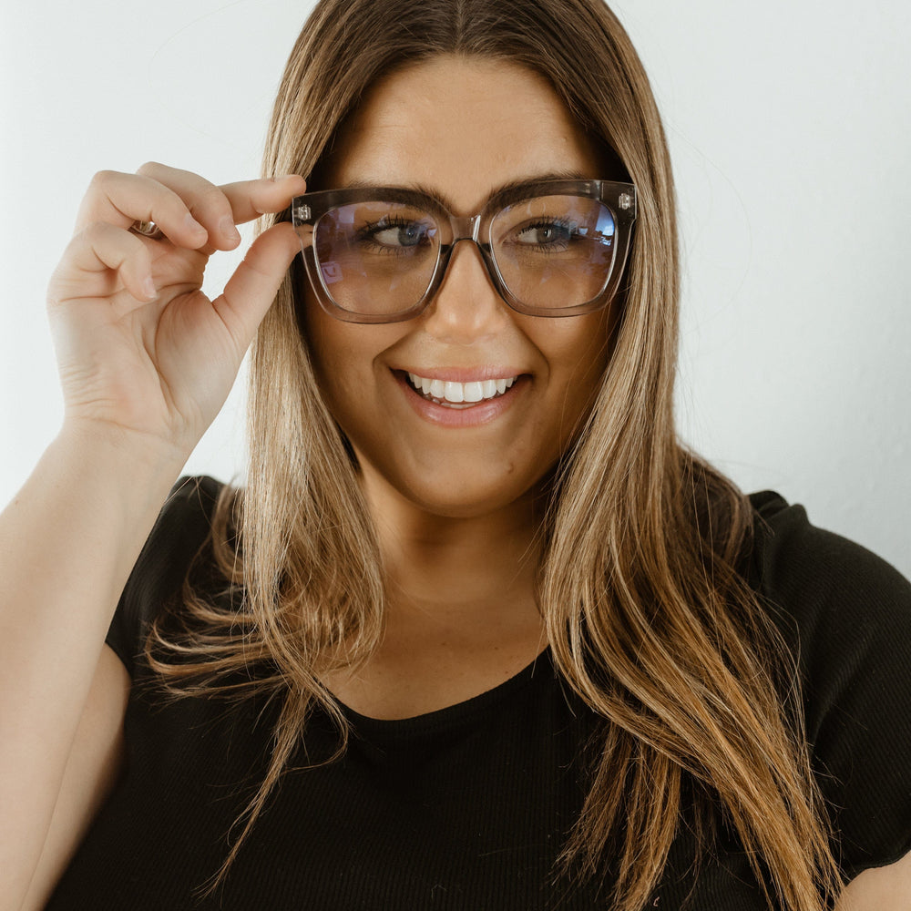 Woman wearing glasses and smiling against a white background