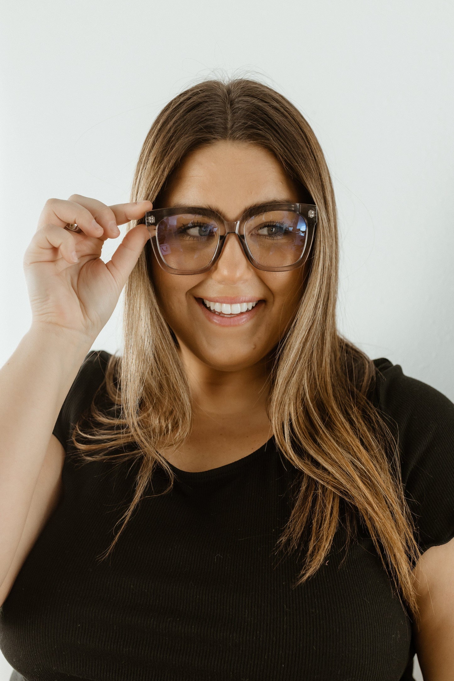 Woman wearing glasses and smiling against a white background