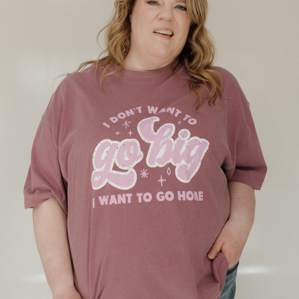 Person wearing a berry t-shirt with pink text against a plain background