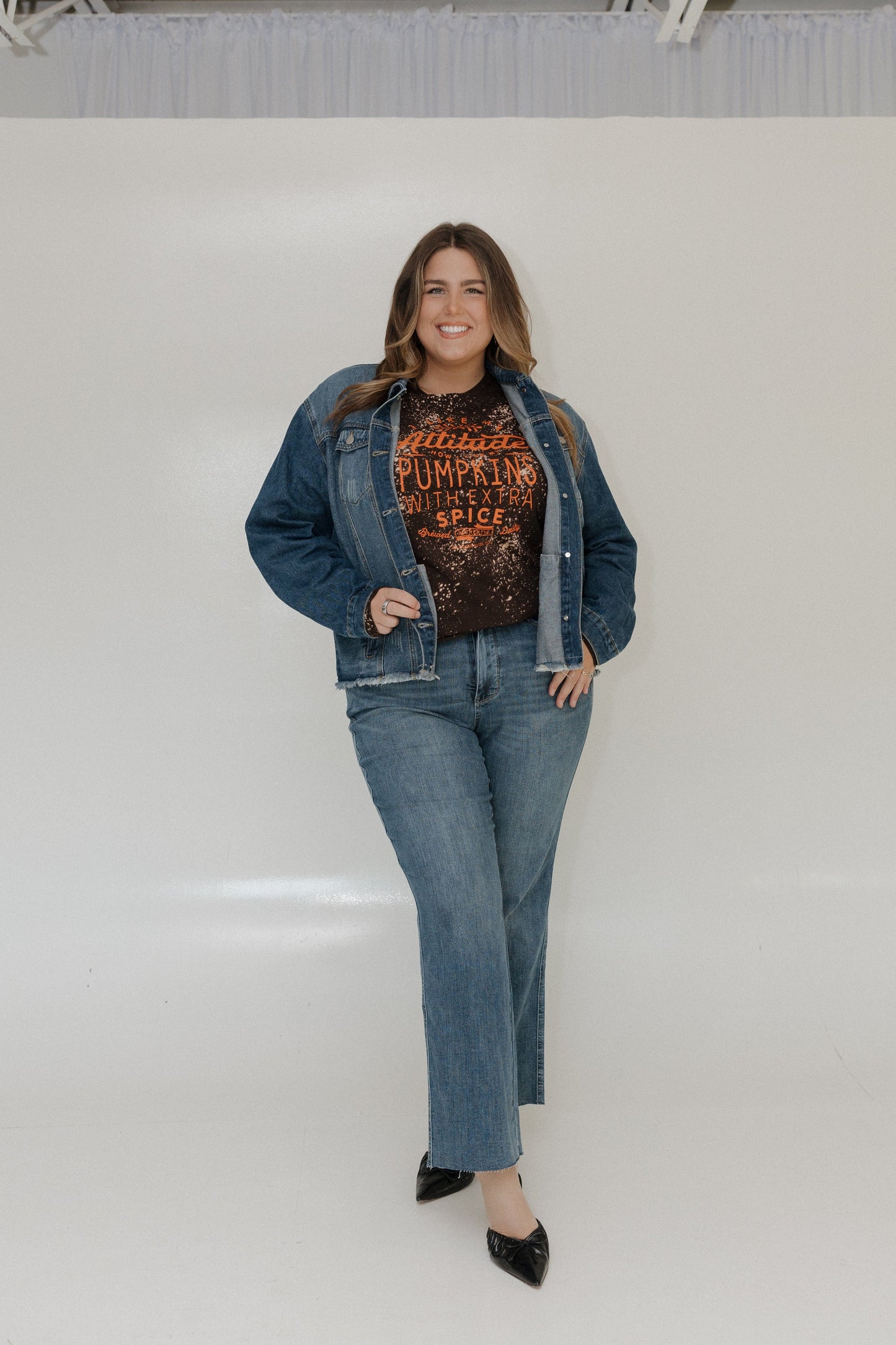 "I LIKE MY ATTITUDE HOW I LIKE MY PUMPKINS WITH EXTRA SPICE" LONG-SLEEVE TEE Love Marlow Woman wearing a denim jacket and jeans with a graphic t-shirt against a white background