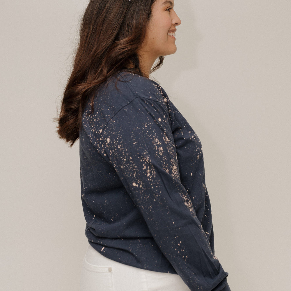 Woman wearing a dark blue distressed denim jacket against a plain background