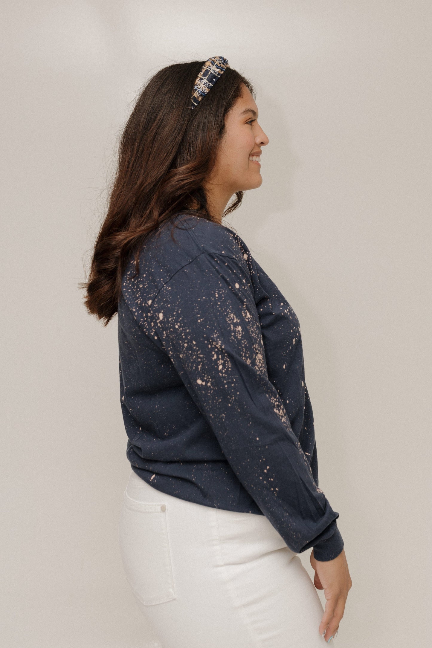 Woman wearing a dark blue distressed denim jacket against a plain background