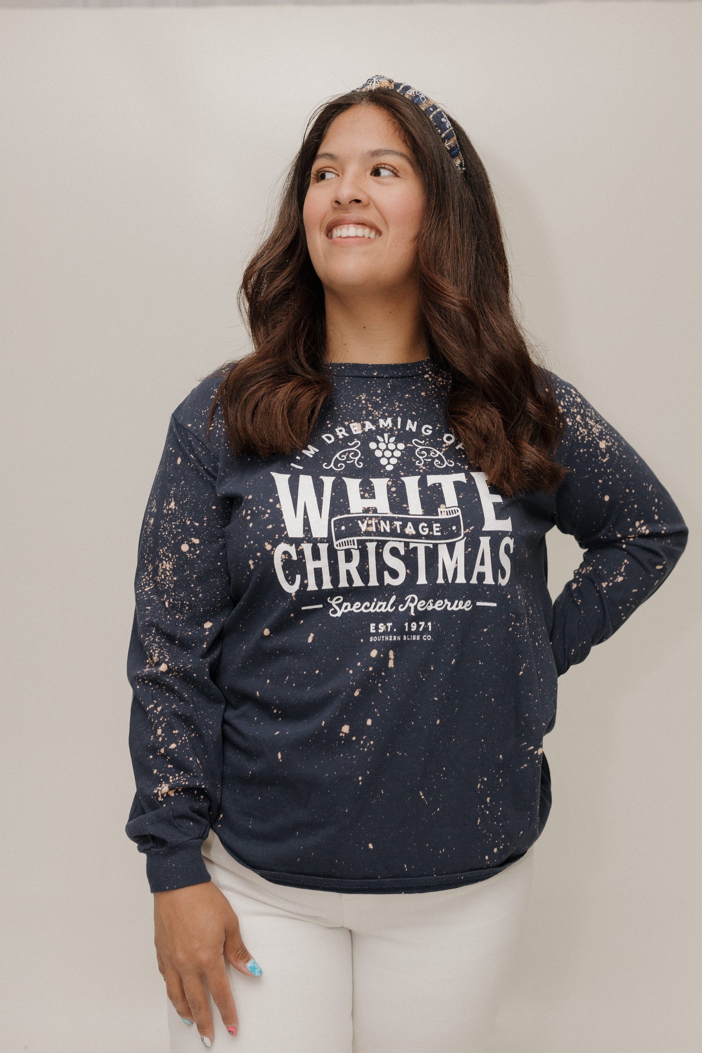 Woman wearing a navy sweatshirt with 'White Christmas' text against a plain background