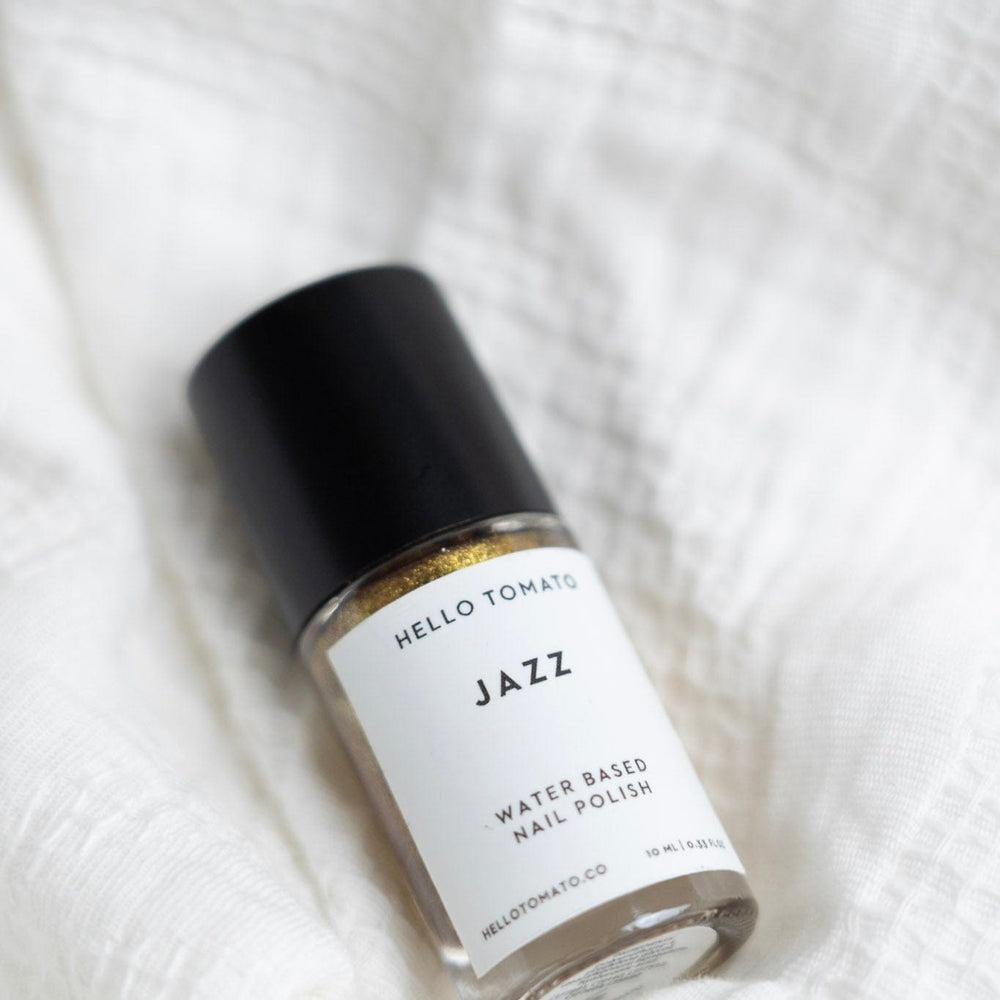 Bottle of 'Jazz' water-based nail polish by Hello Tomato on a white textured background