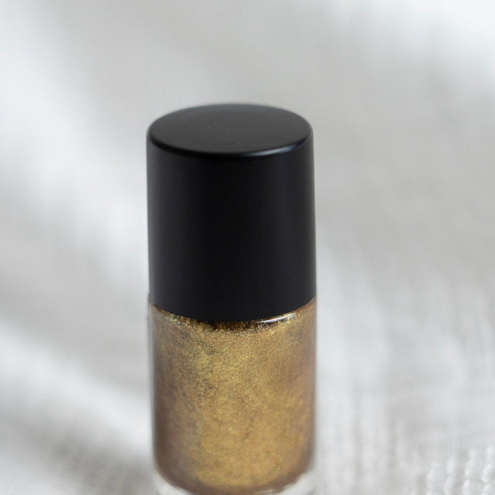 Gold nail polish with black cap on a white background