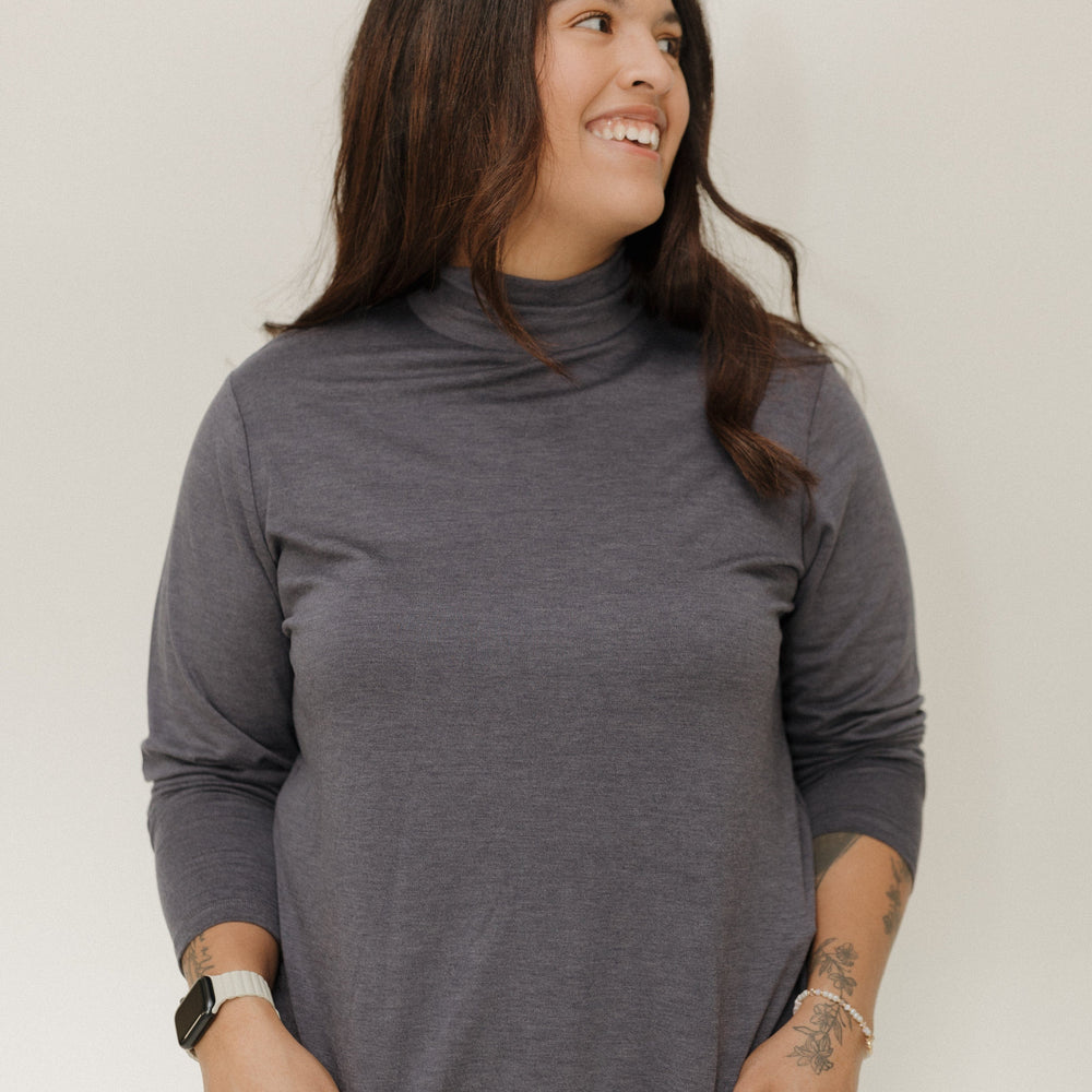 Woman wearing a gray turtleneck sweater against a white background