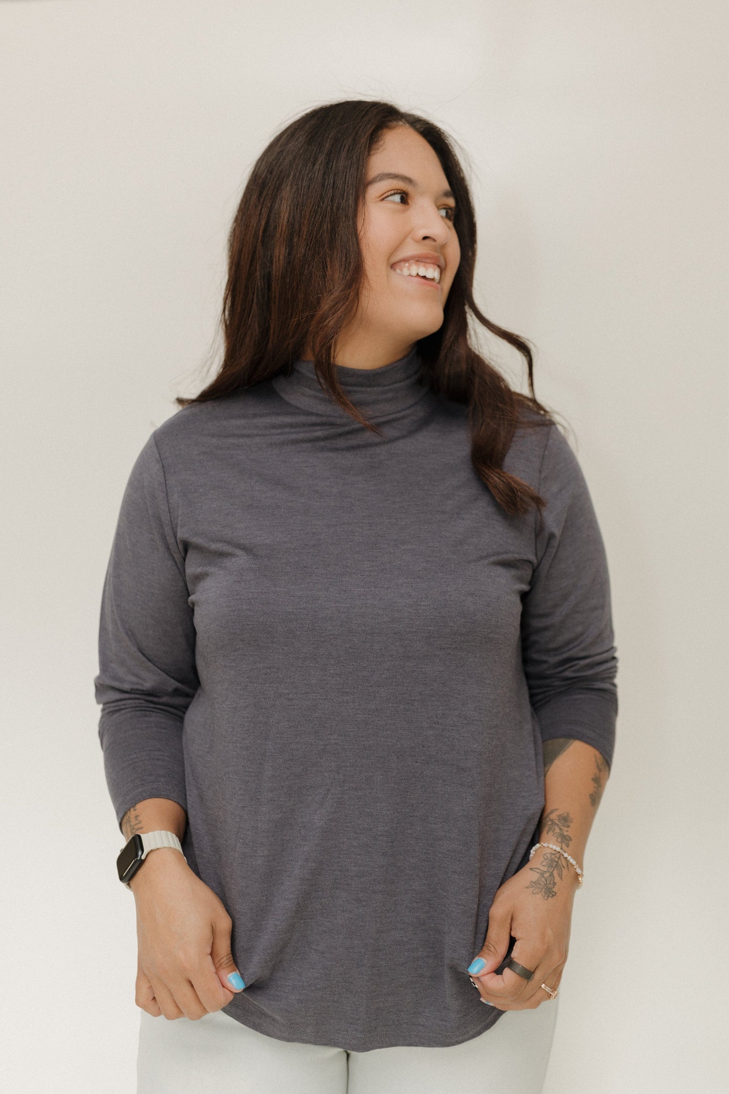 Woman wearing a gray turtleneck sweater against a white background