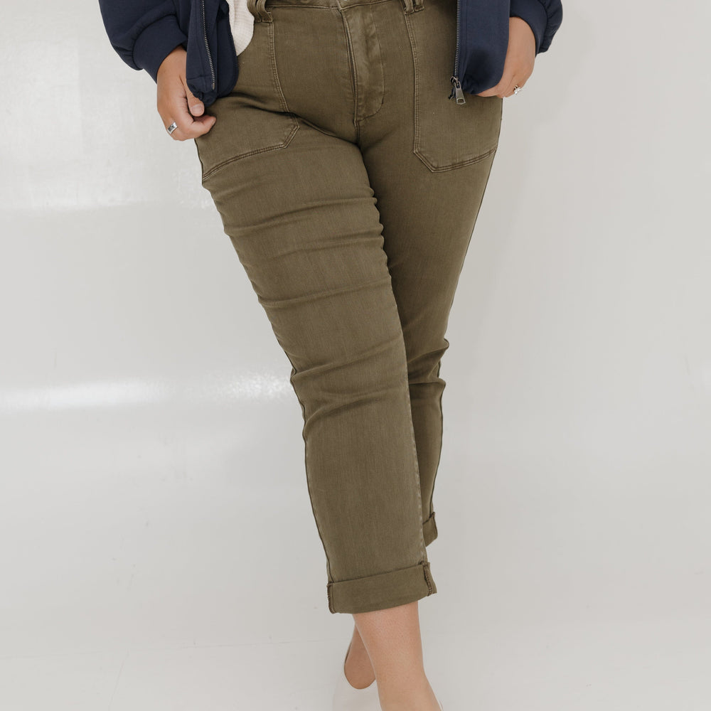 Person wearing olive green pants with a white background