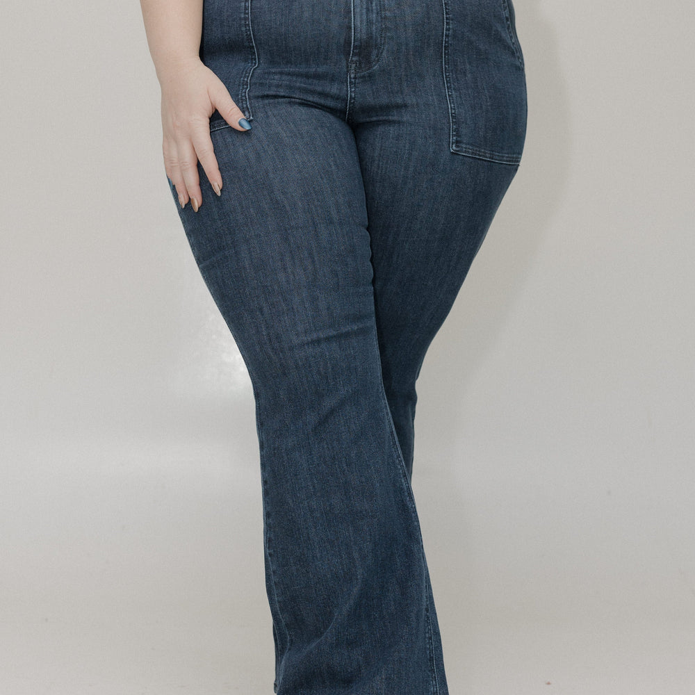 Person wearing blue jeans and a black top on a plain background