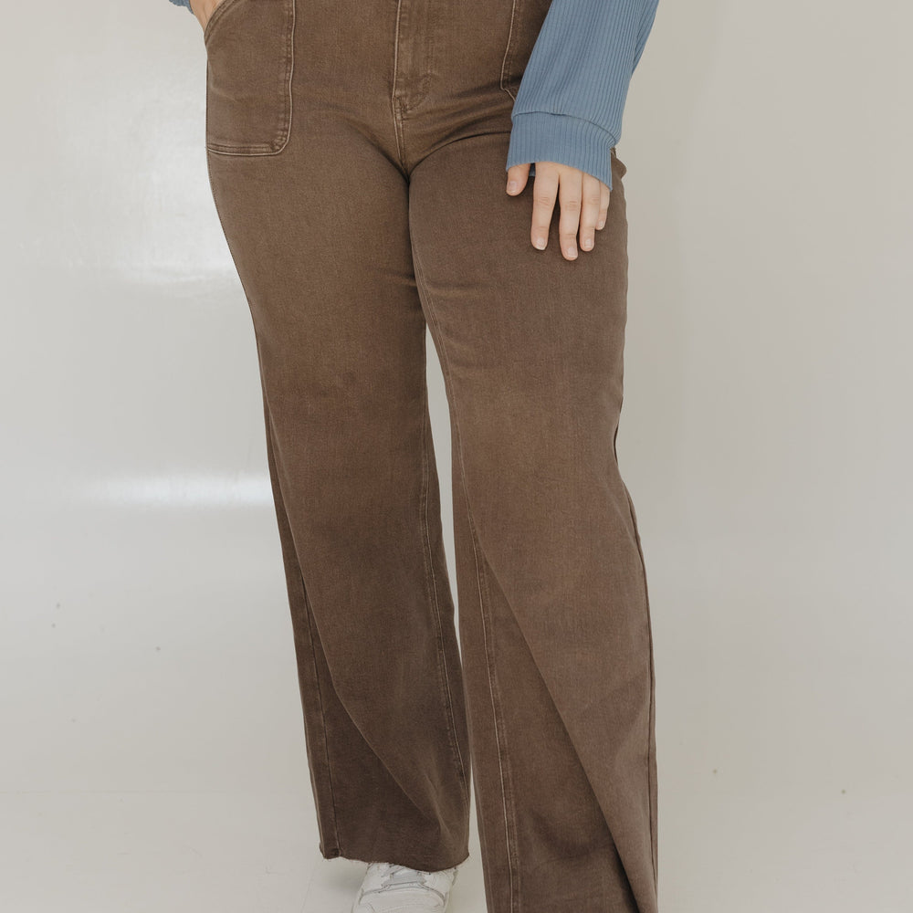 Person wearing brown corduroy pants and a blue sweater on a white background