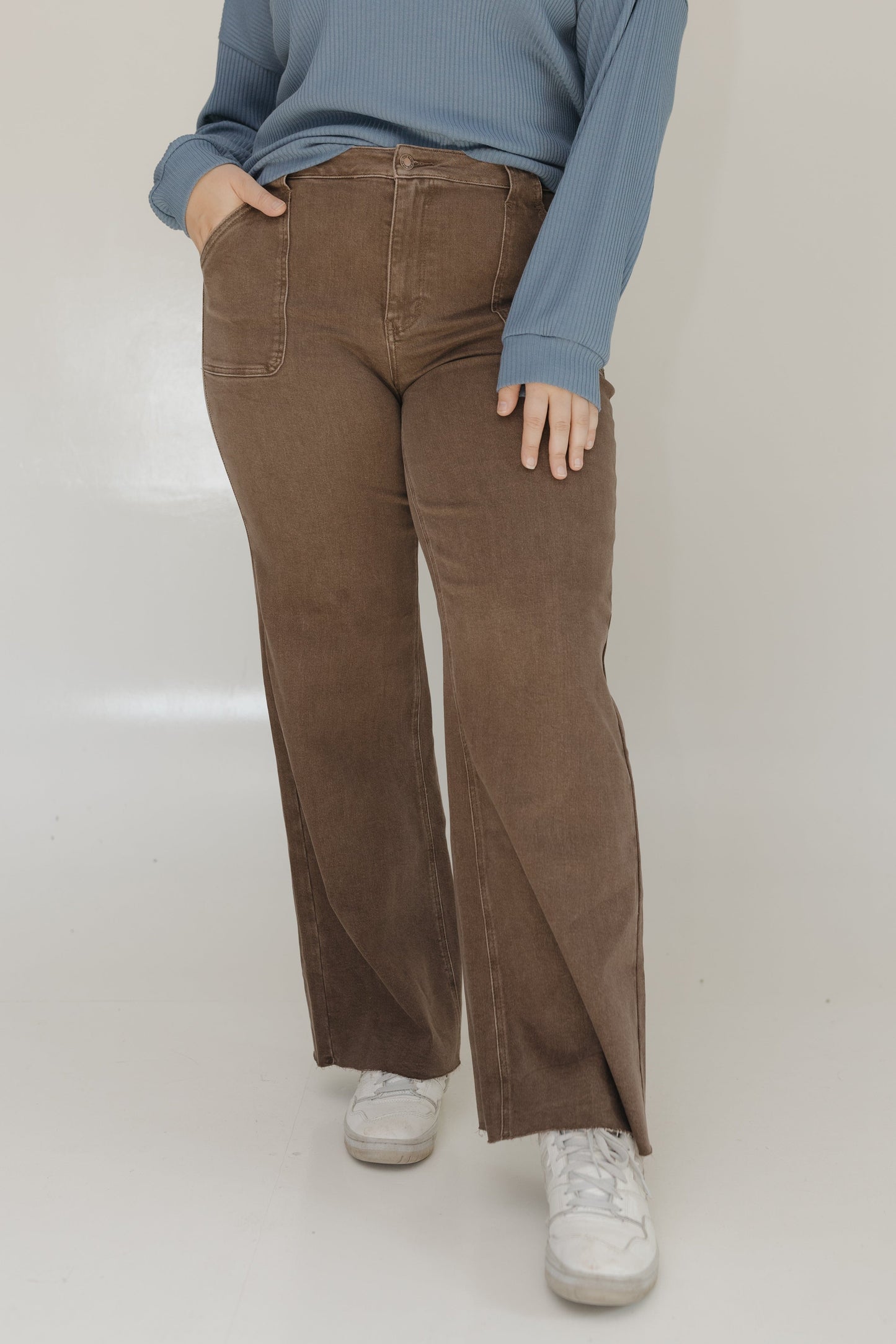 Person wearing brown corduroy pants and a blue sweater on a white background