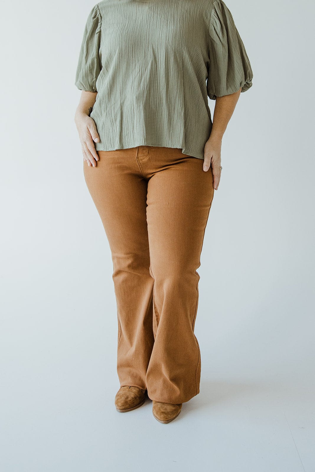 Person wearing a green blouse and Judy Blue High Waist Tummy Control Flare jeans in Urban Bronze, standing against a plain background.