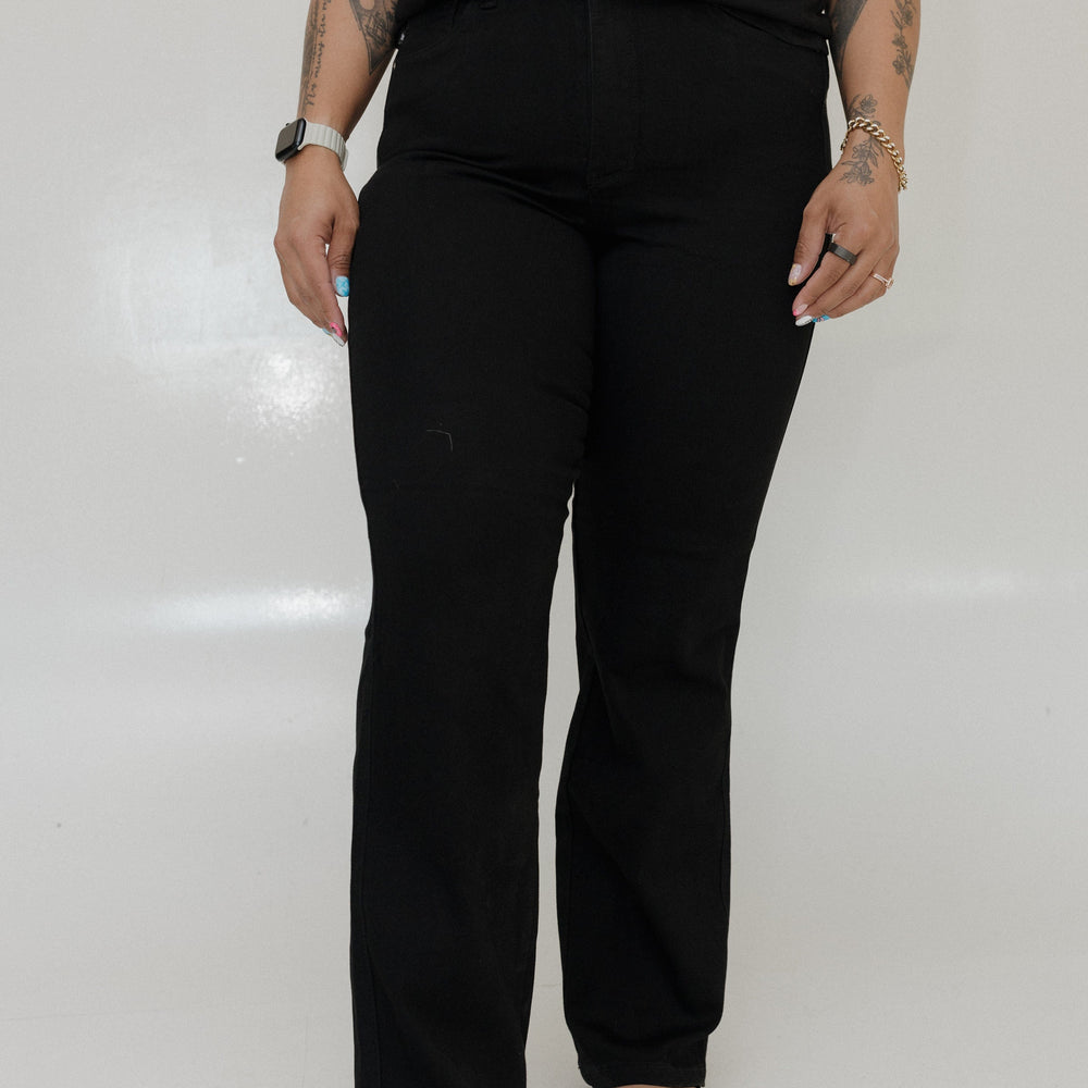 Person wearing black pants and a black top on a white background