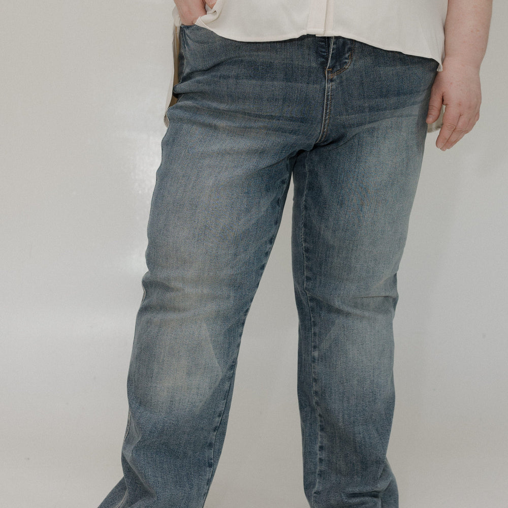 Person wearing blue jeans and a white shirt on a plain background