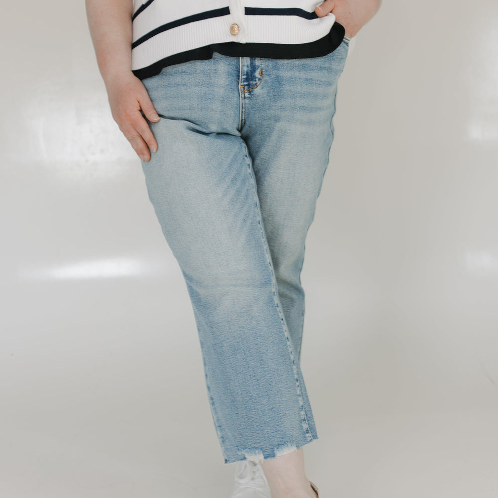 Person wearing a striped shirt and light blue jeans on a white background