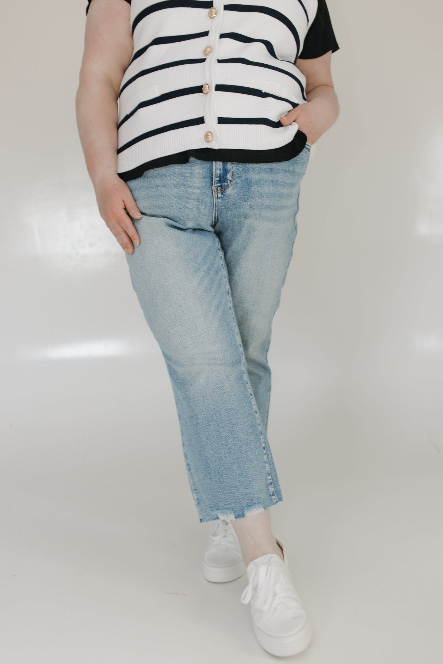 Person wearing a striped shirt and light blue jeans on a white background