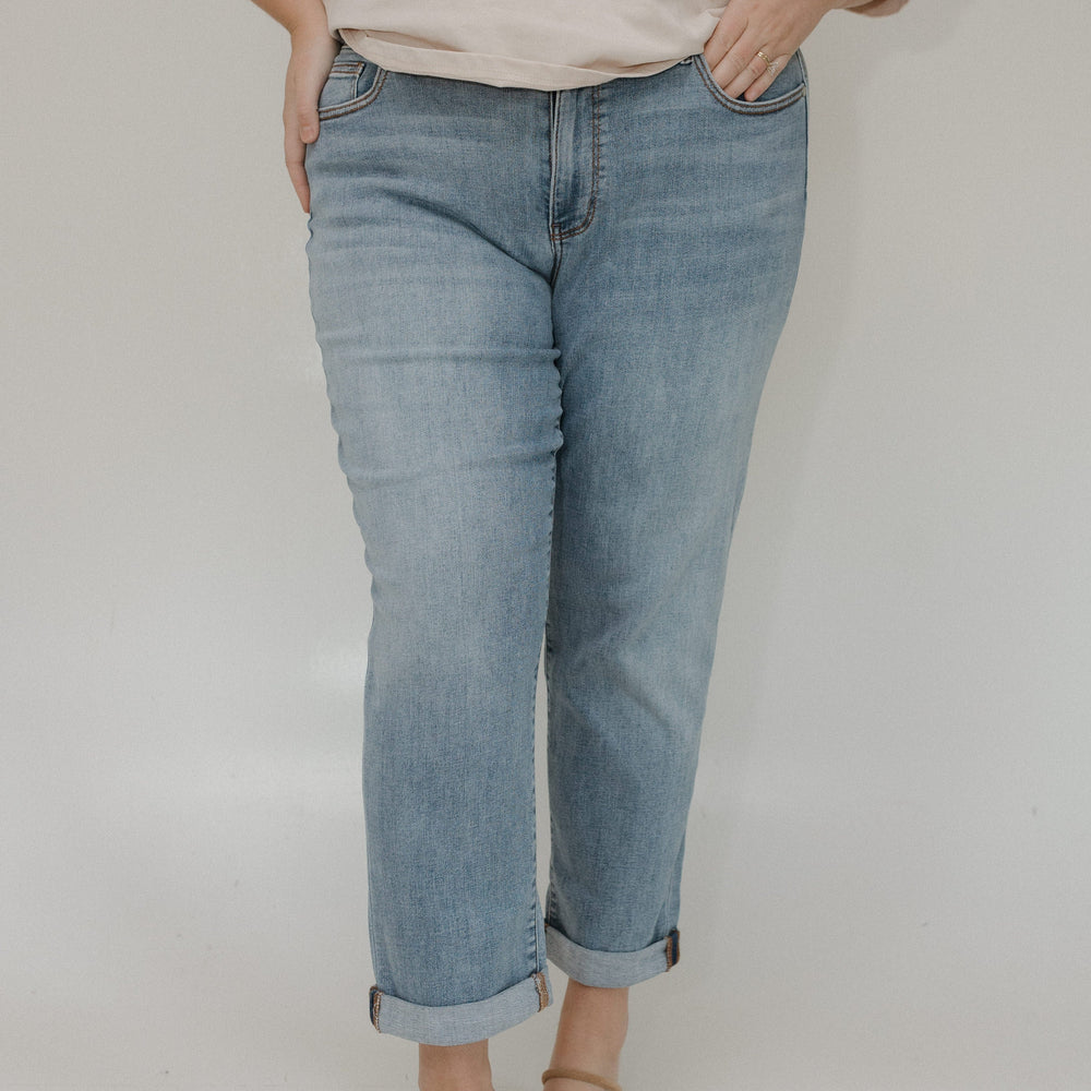 Person wearing light blue jeans and a beige top on a plain background