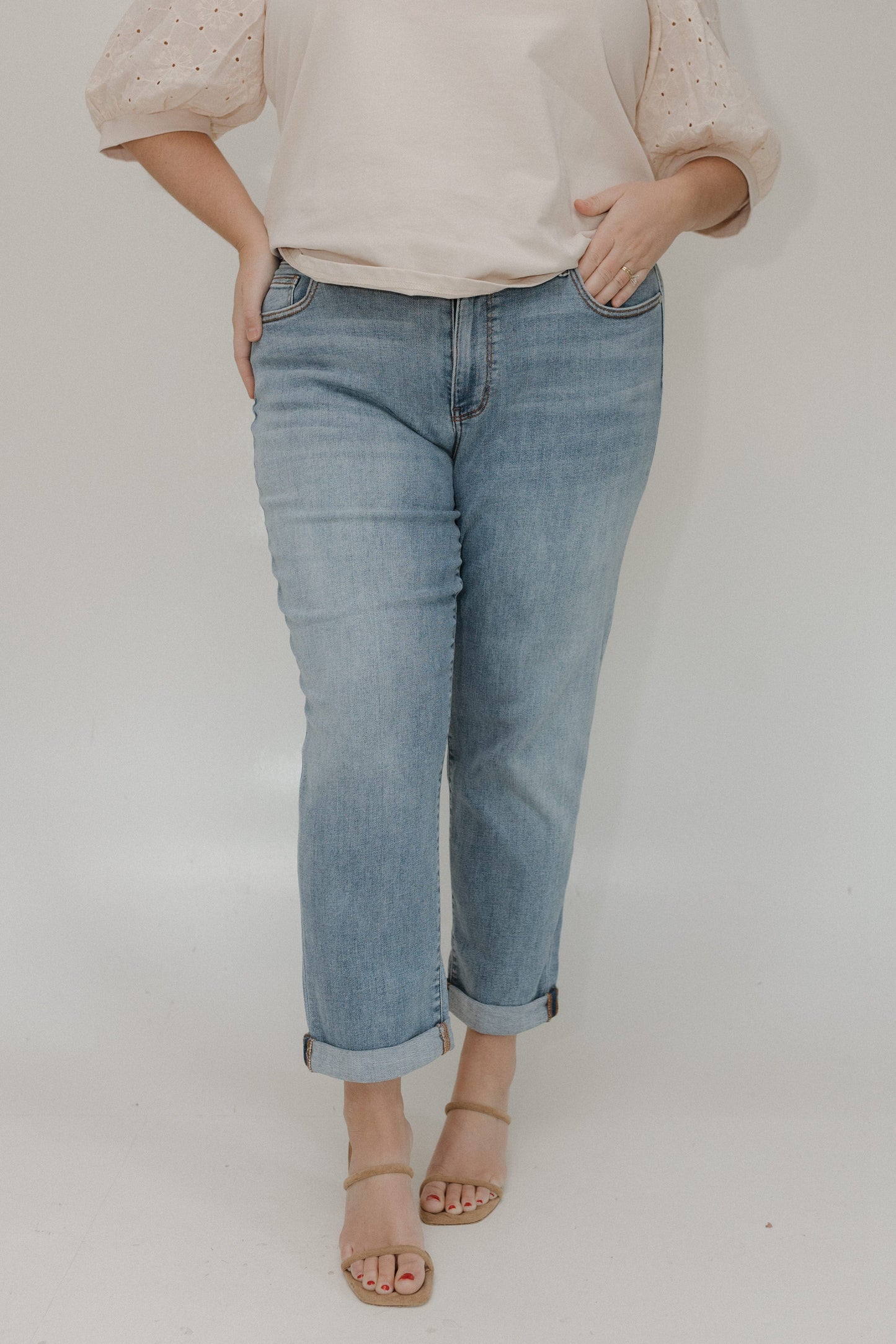 Person wearing light blue jeans and a beige top on a plain background