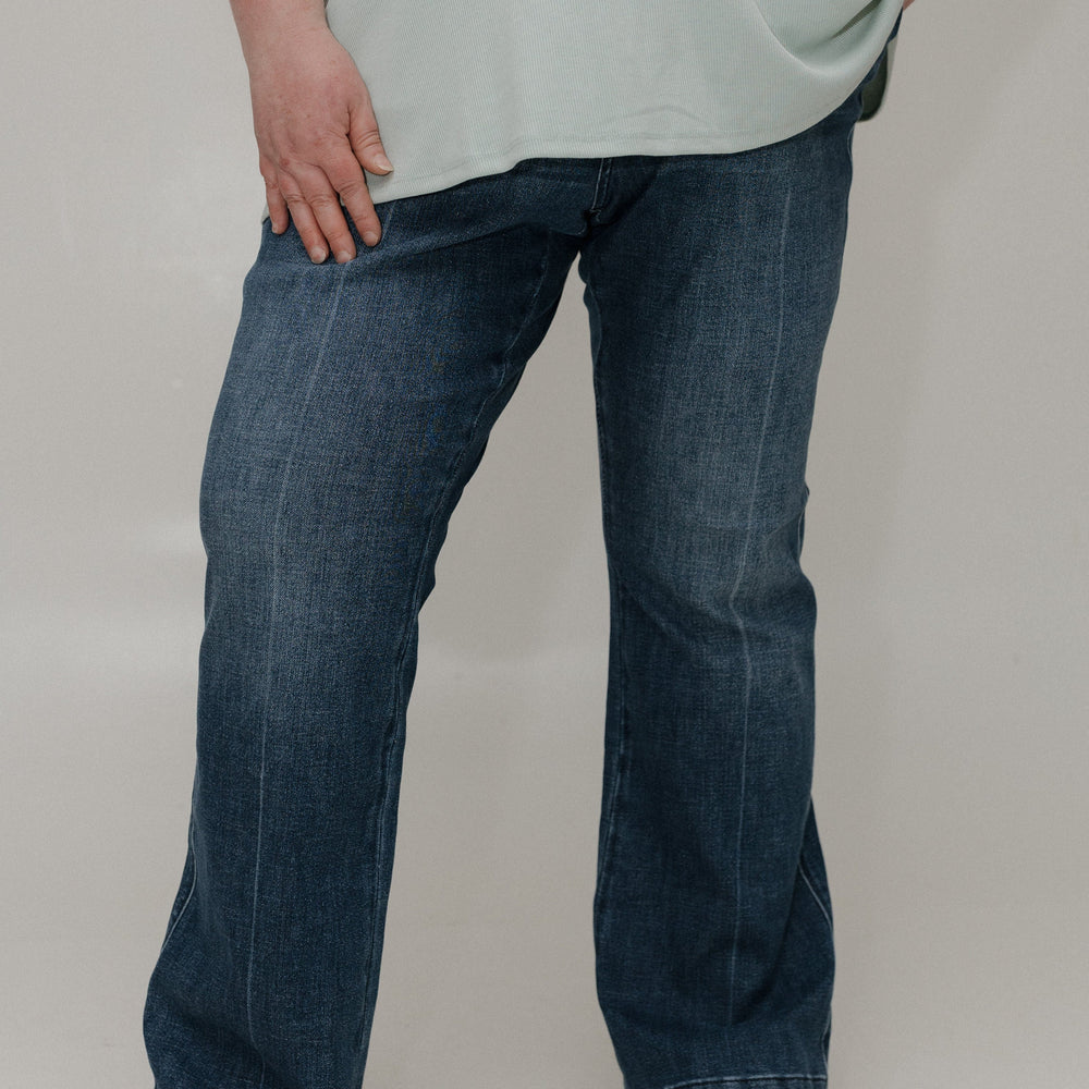 Person wearing blue jeans and a light-colored shirt on a plain background