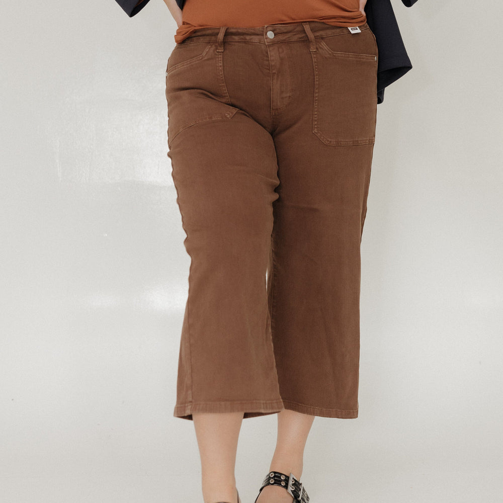 Person wearing a brown top and pants with a black jacket on a white background