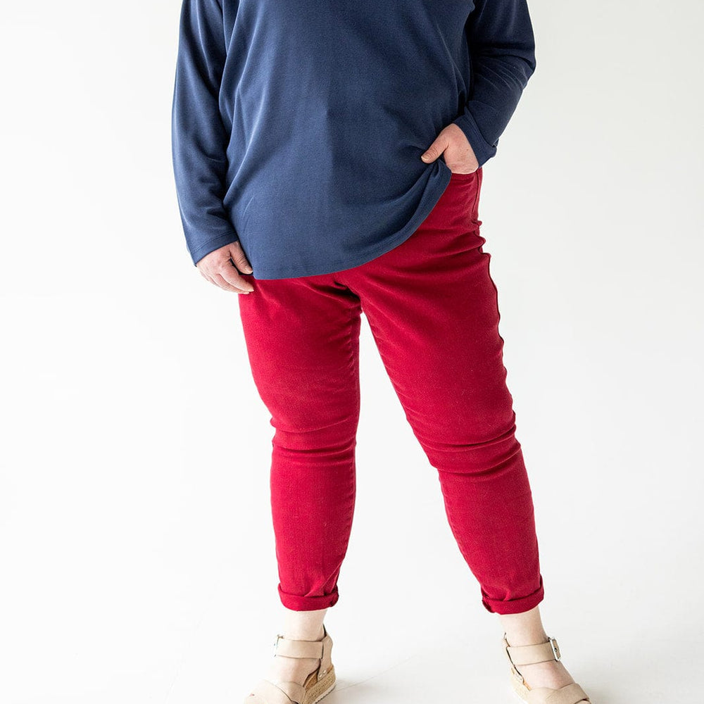 Person wearing a long-sleeve navy blue shirt, Judy Blue Tummy Control Skinny Jeans in Scarlet, and beige sandals, standing against a plain white background. Face is not visible.