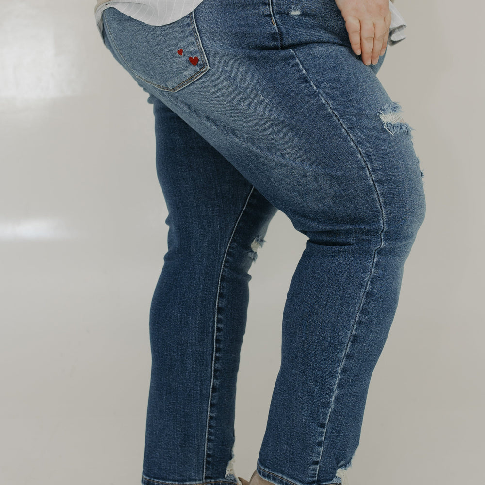 Person wearing blue jeans and a beige top on a plain background