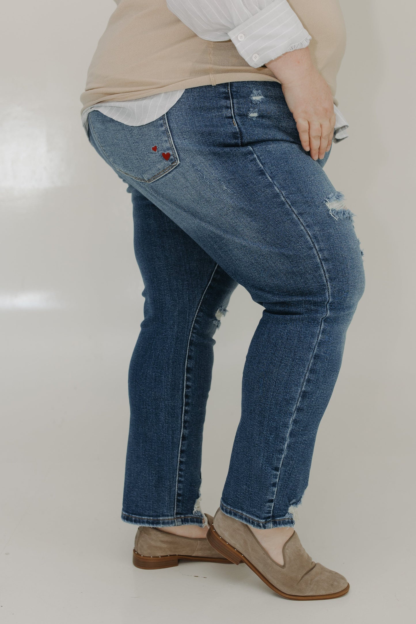 Person wearing blue jeans and a beige top on a plain background