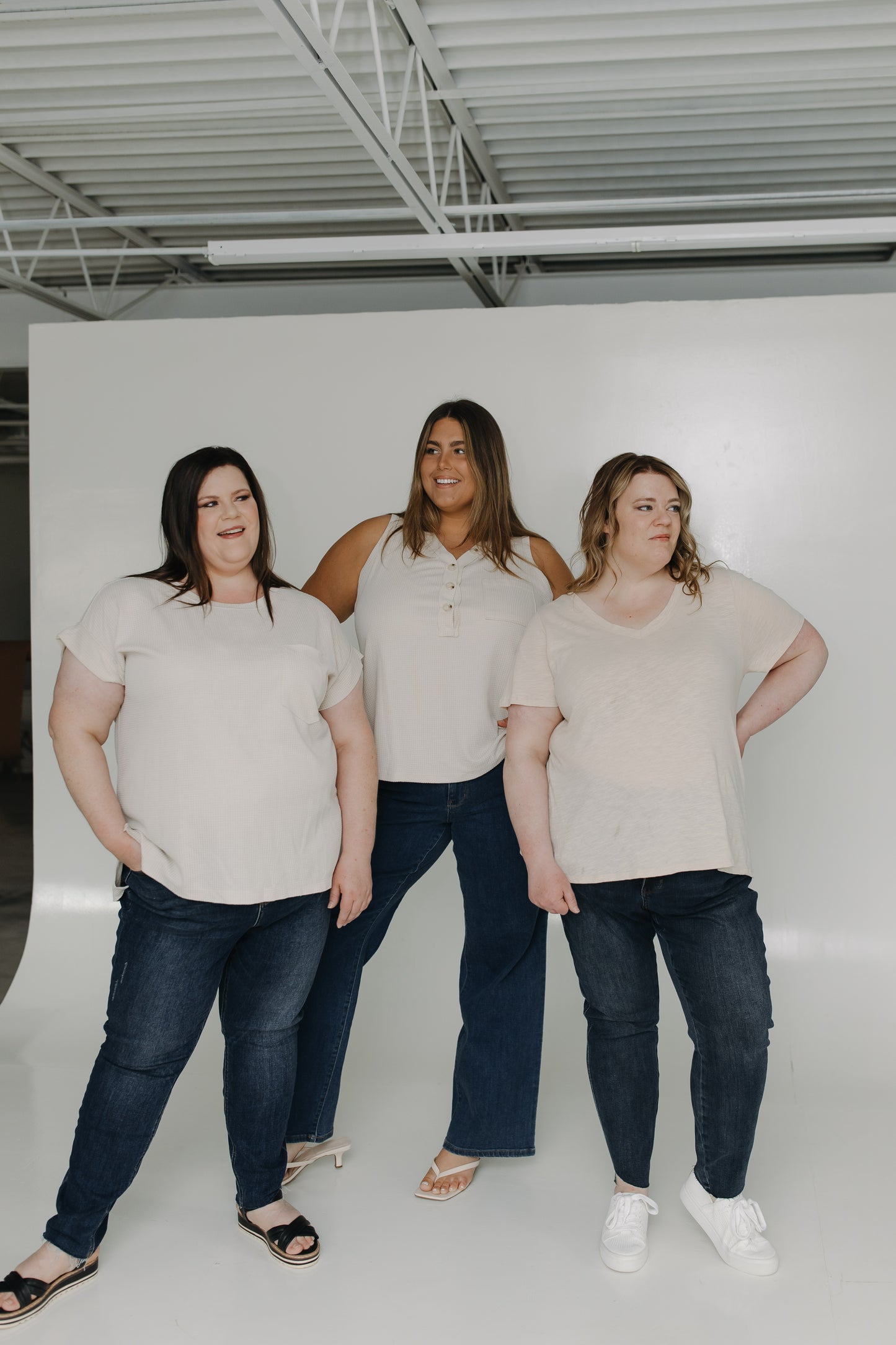 Three women posing together in a warehouse setting