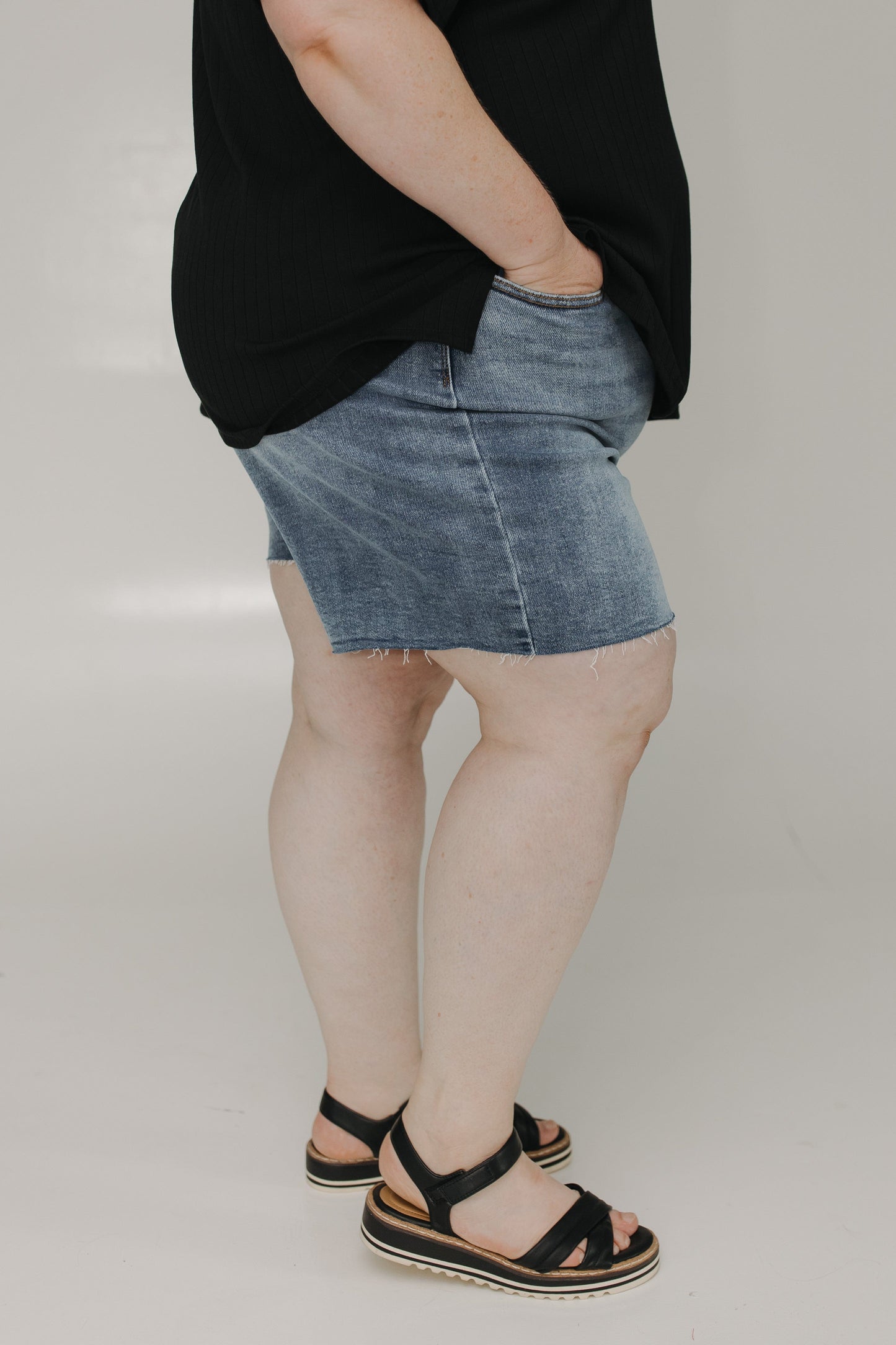 Person wearing a black top and denim skirt on a plain background