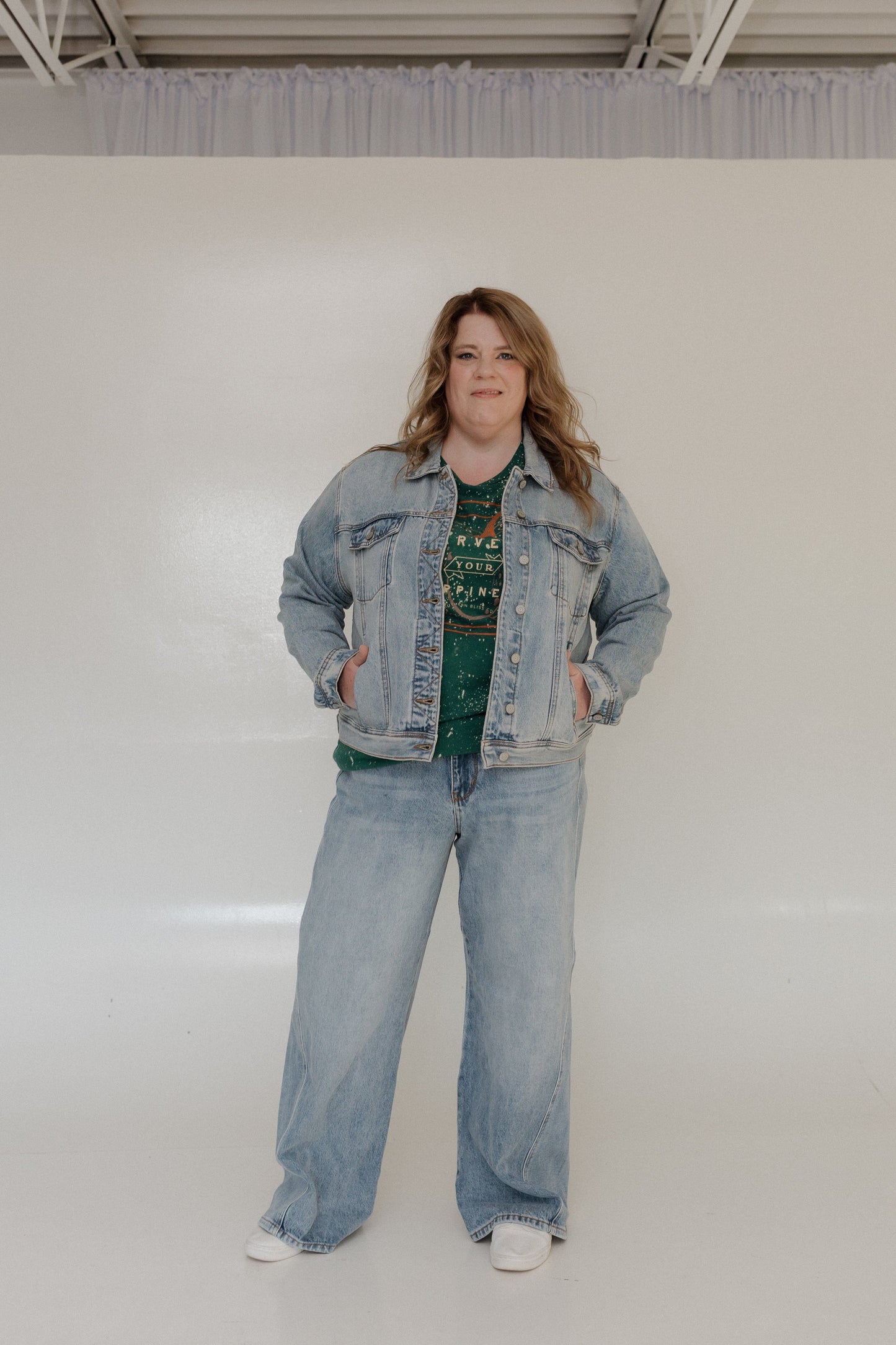Person wearing a denim jacket and jeans against a plain background