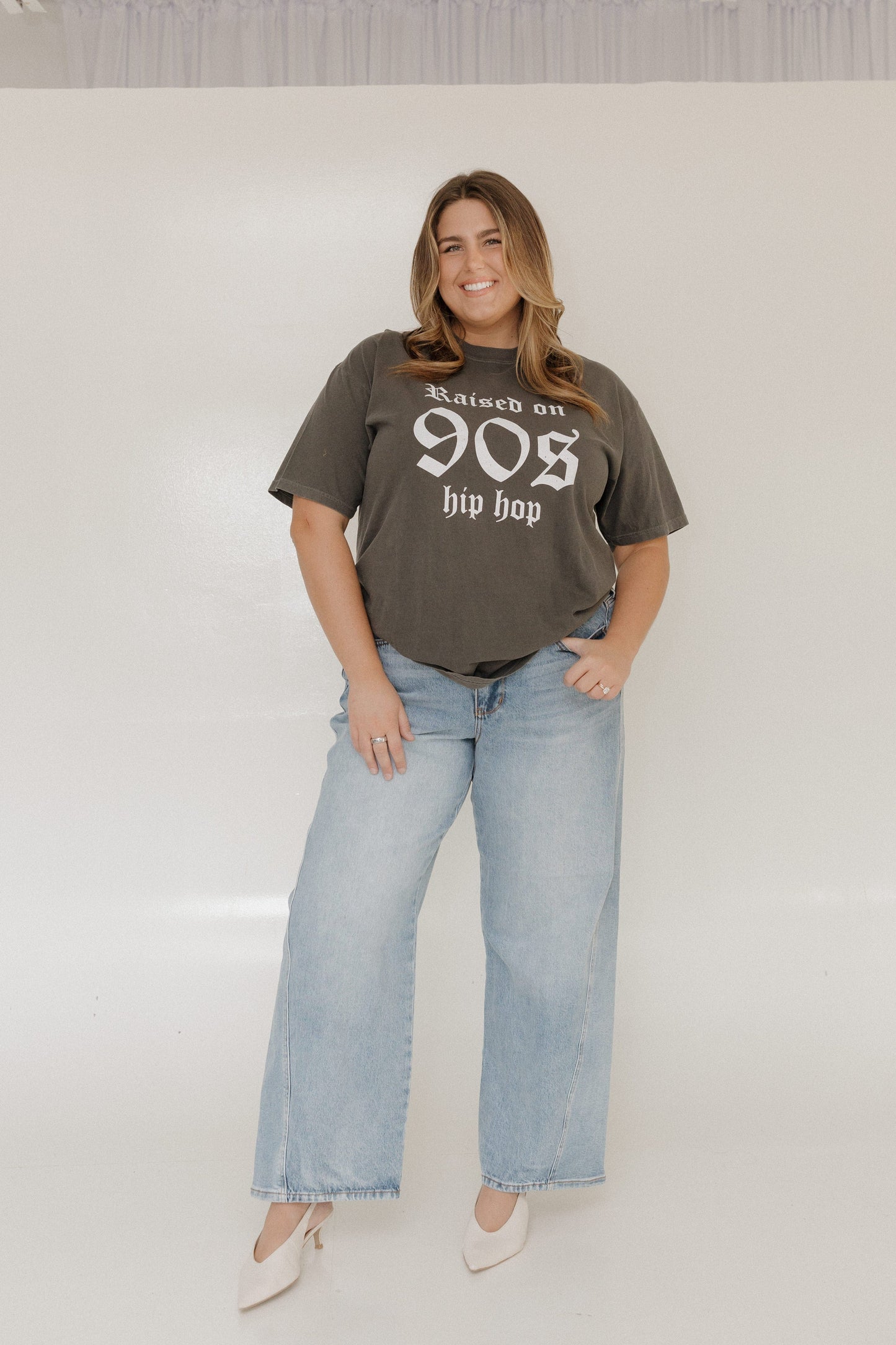 Woman wearing a graphic t-shirt and jeans on a plain background