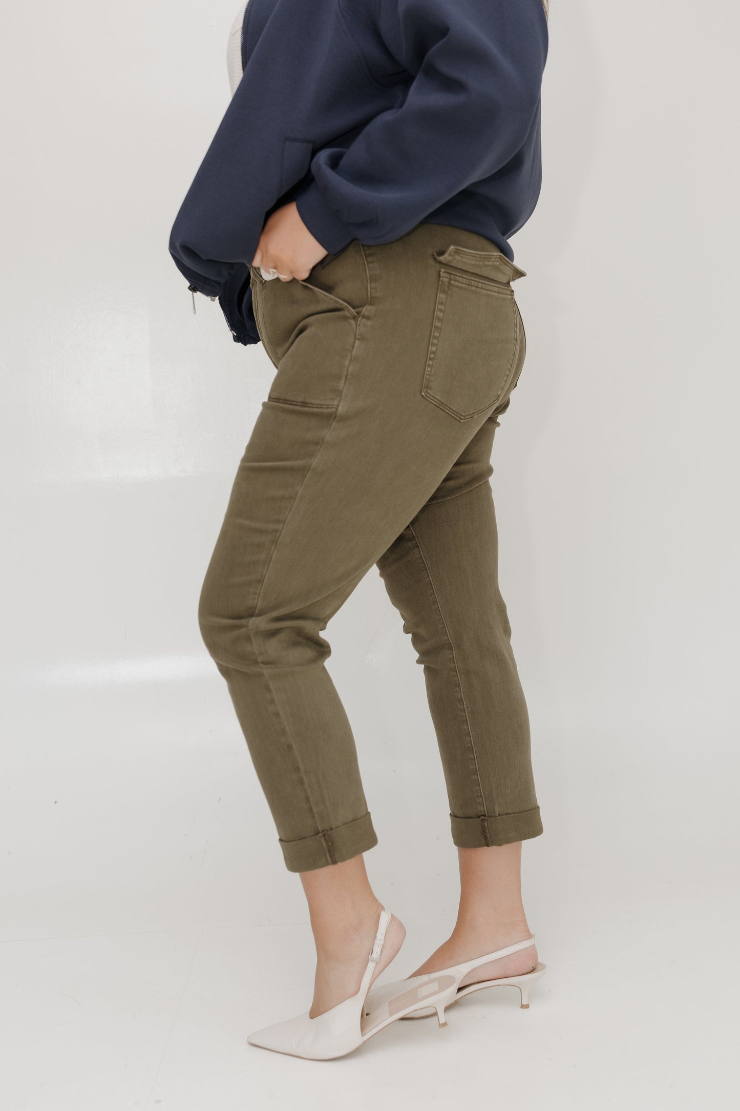 Person wearing olive green cargo pants and a navy sweatshirt on a white background
